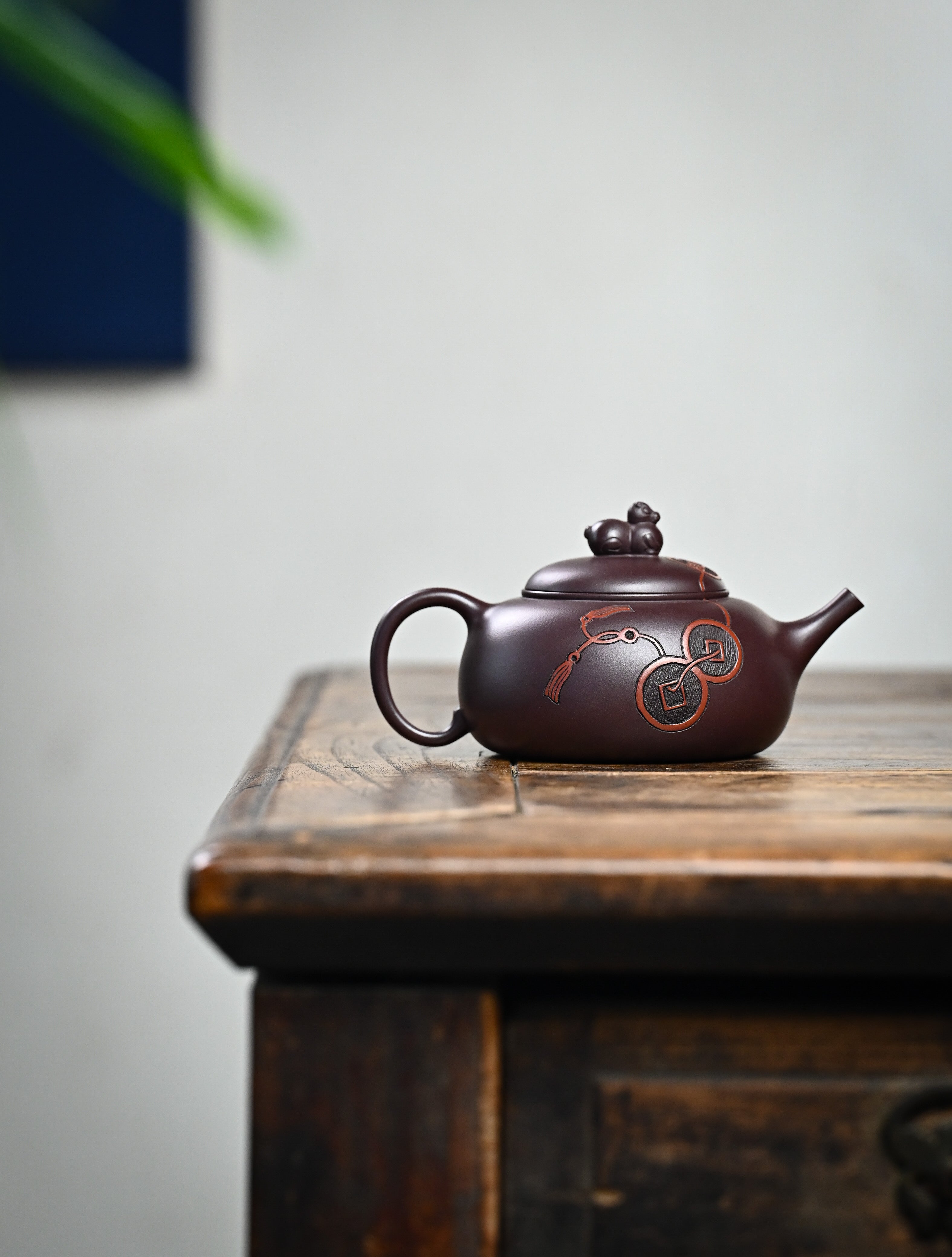 YANYOO handmade Yixing teapot featuring Zini clay and ancient Chinese coin sculpture, lifestyle wide-angle right side.