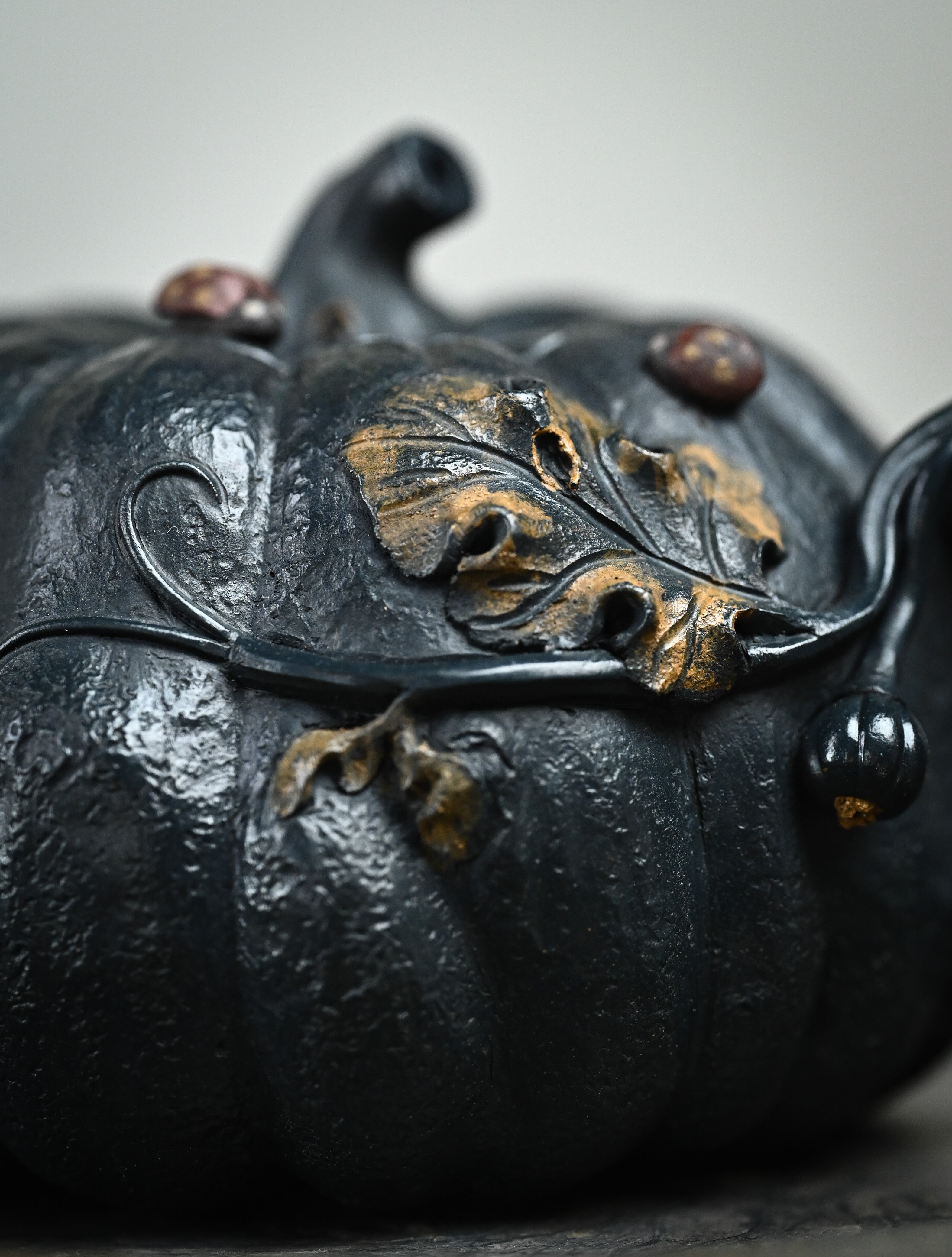 YANYOO handmade Yixing teapot featuring "Que Tou Qing" lvni clay and a lifelike pumpkin shape, lifestyle detail front side.