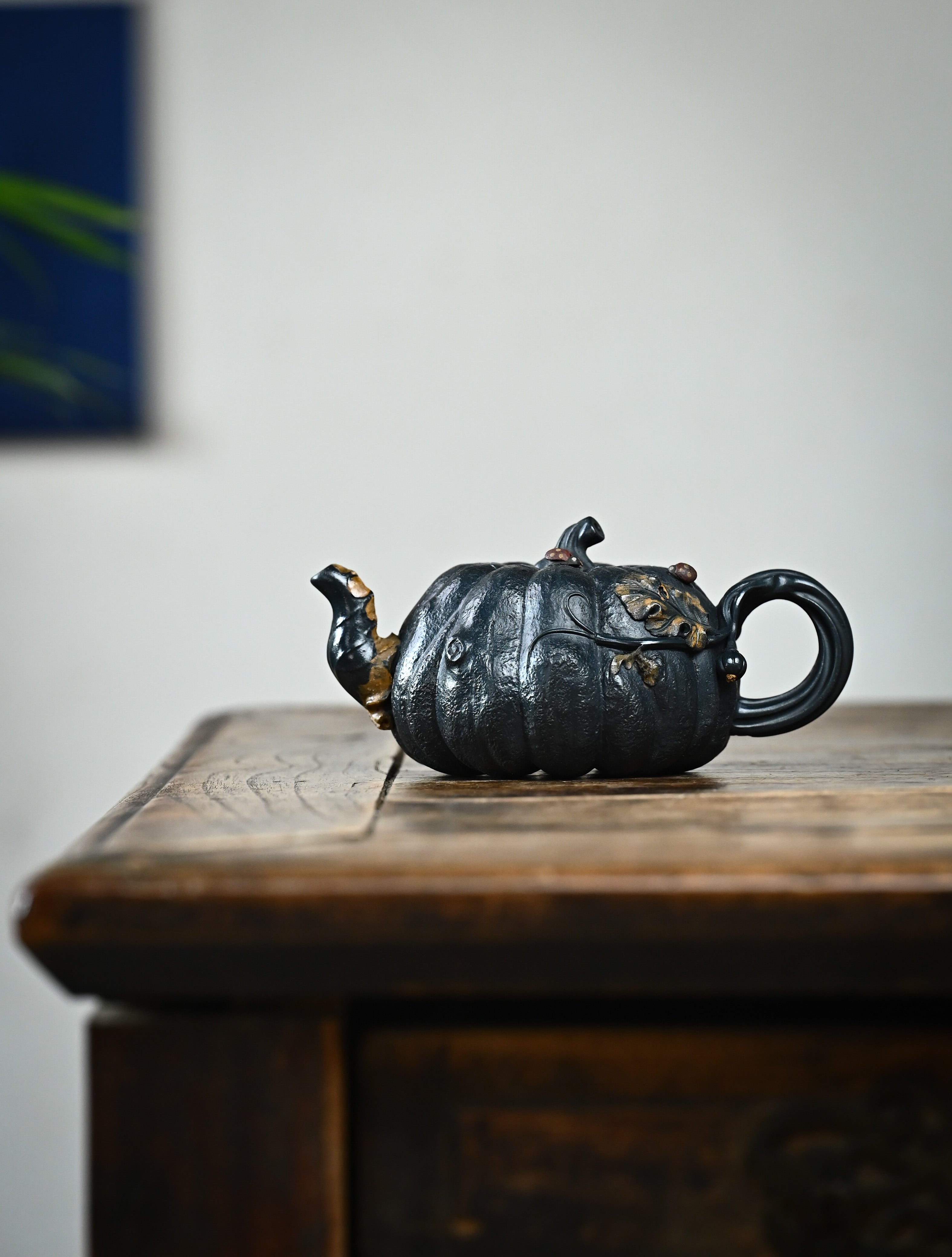 YANYOO handmade Yixing teapot featuring "Que Tou Qing" lvni clay and a lifelike pumpkin shape, lifestyle wide-angle left side.