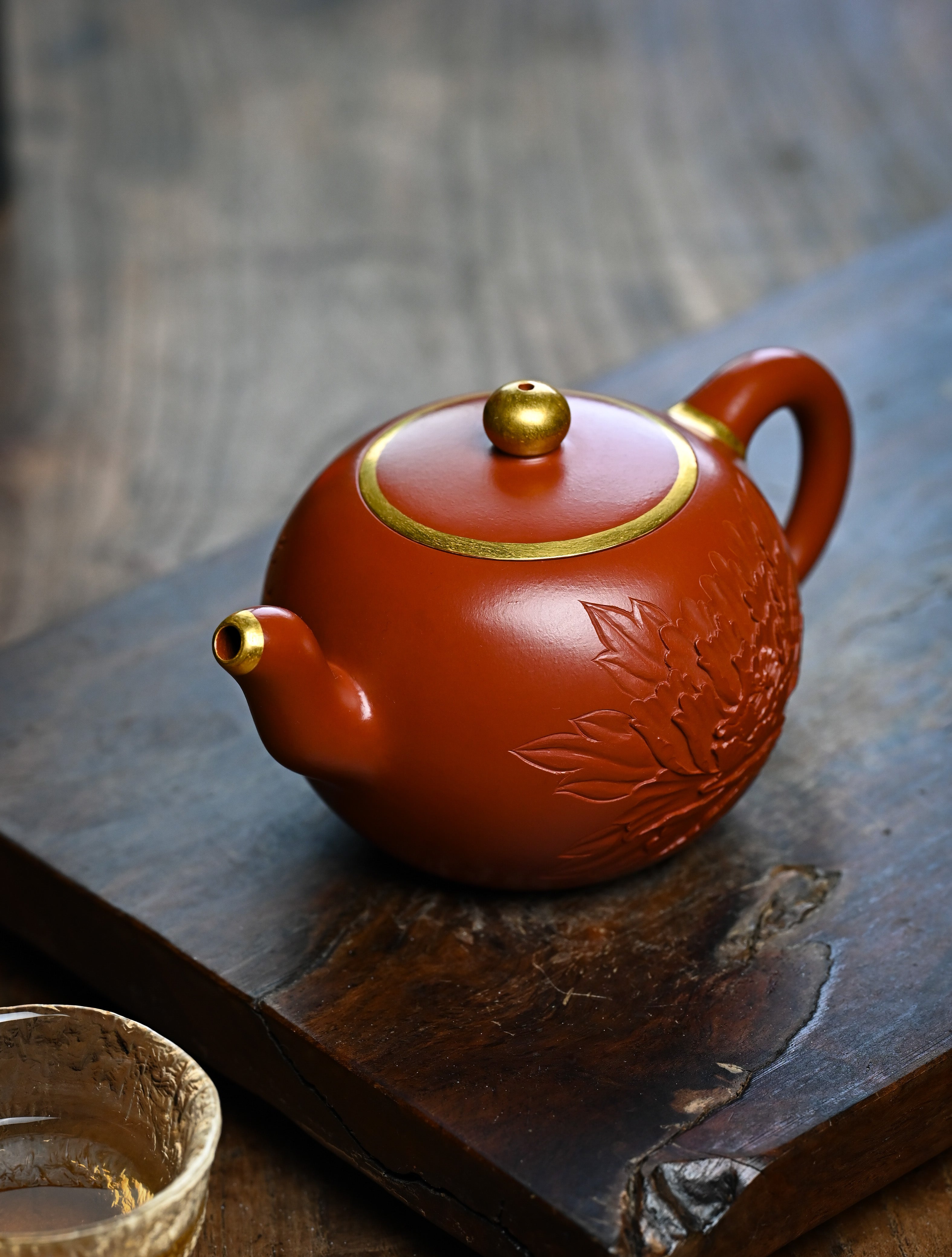 YANYOO handmade Yixing teapot featuring premium Zhuni clay and relief engravings, lifestyle left side.