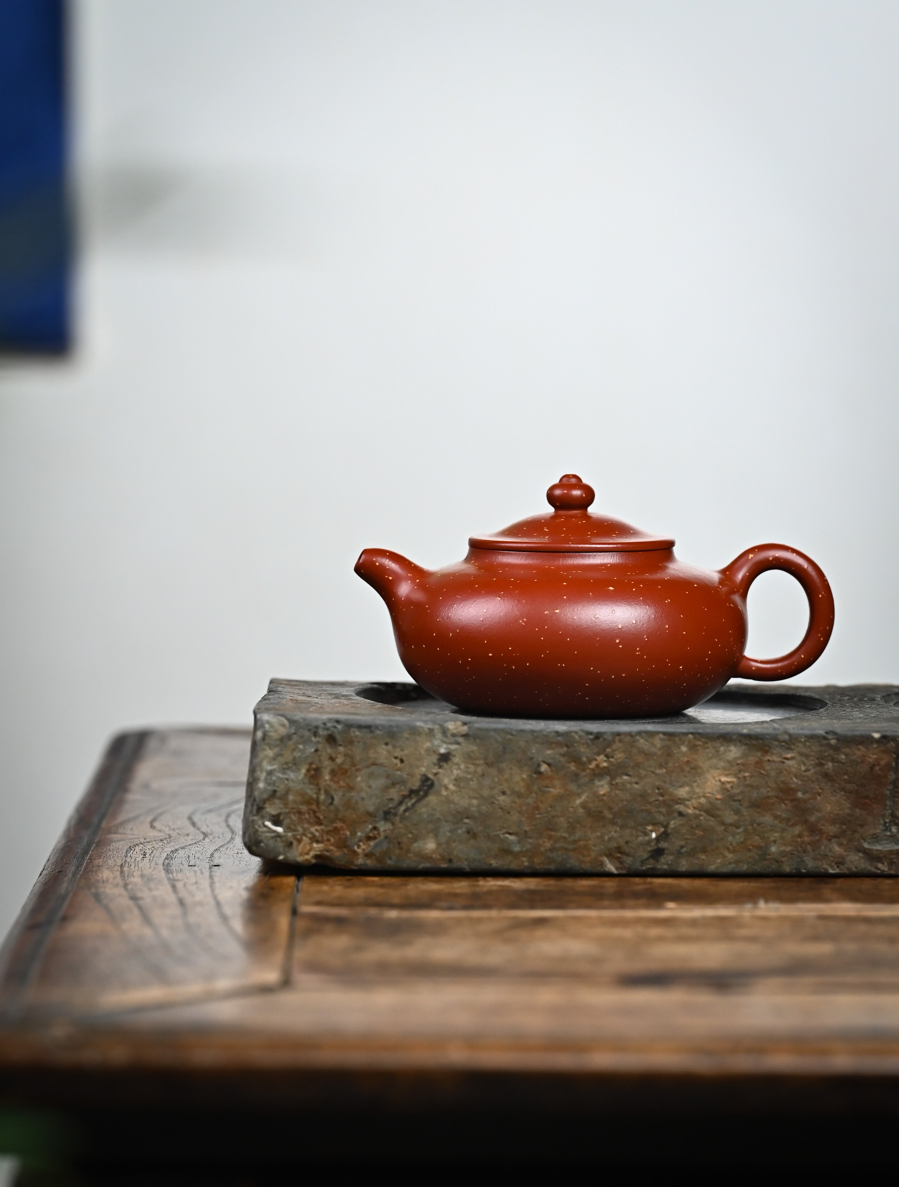 YANYOO handmade Yixing teapot featuring Zhuni Da Hong Pao clay and sand paving technique, lifestyle wide-angle left side.