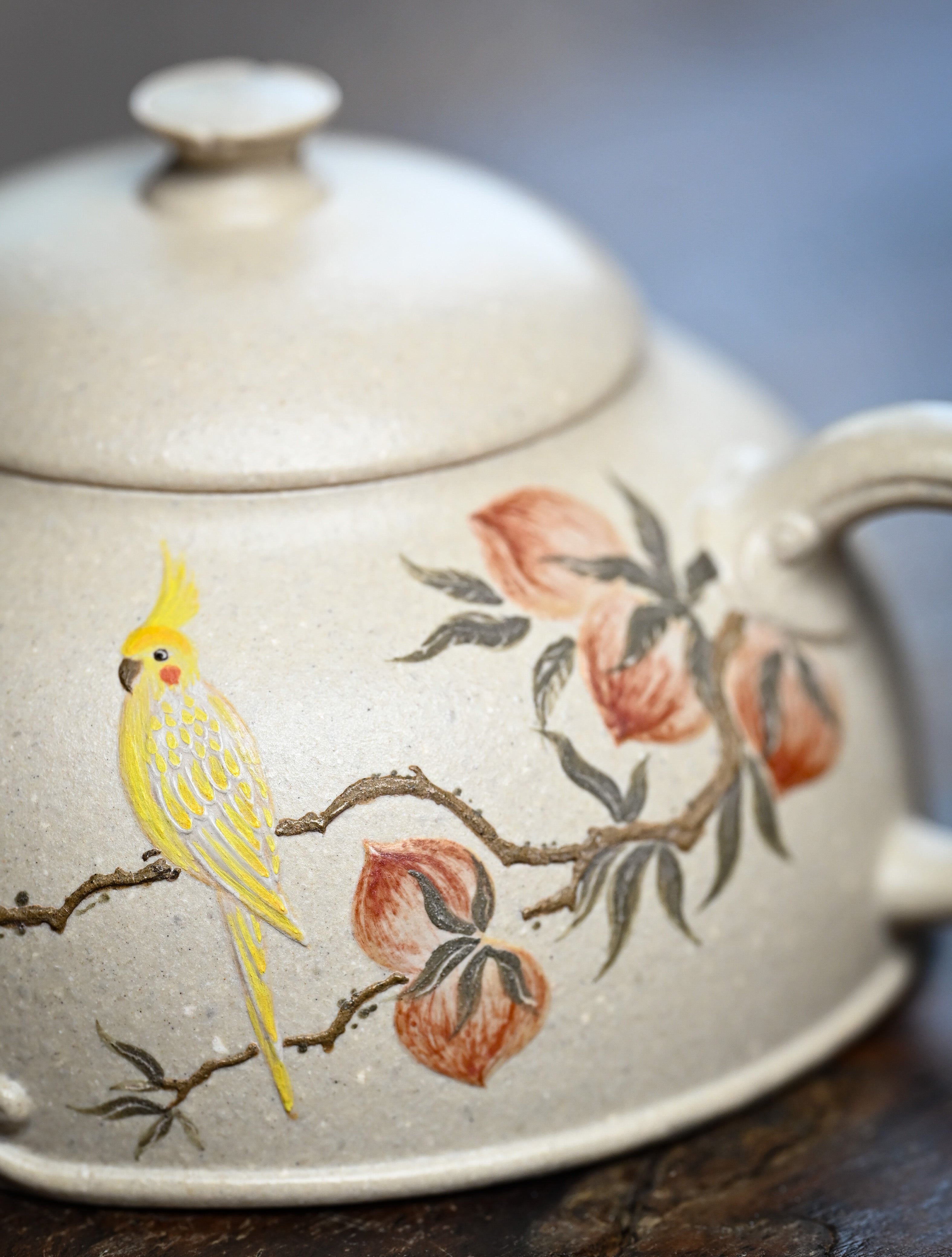 YANYOO handmade Yixing teapot featuring suet white jade Duanni clay and delicate bird-and-peach themed clay painting, lifestyle detail.