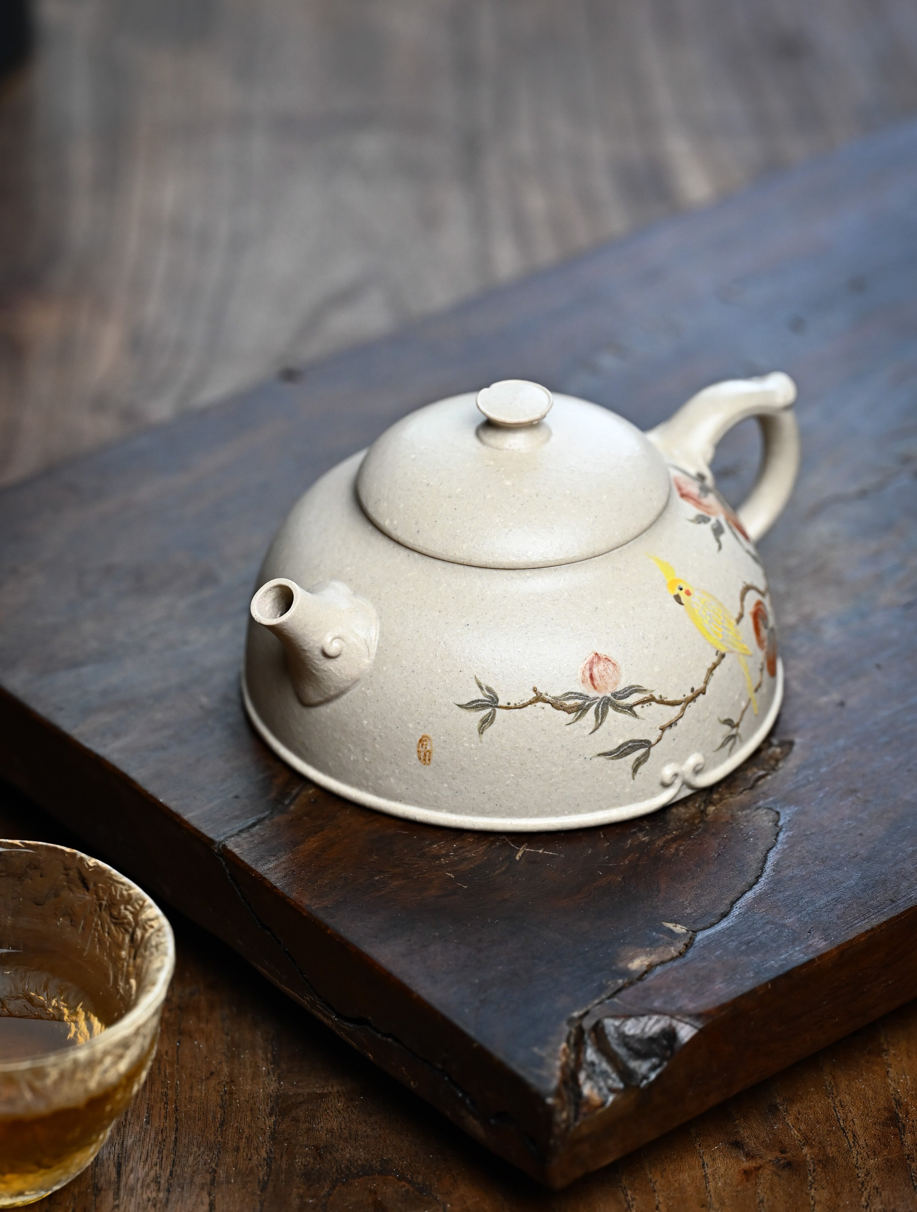 YANYOO handmade Yixing teapot featuring suet white jade Duanni clay and delicate bird-and-peach themed clay painting, lifestyle left side.