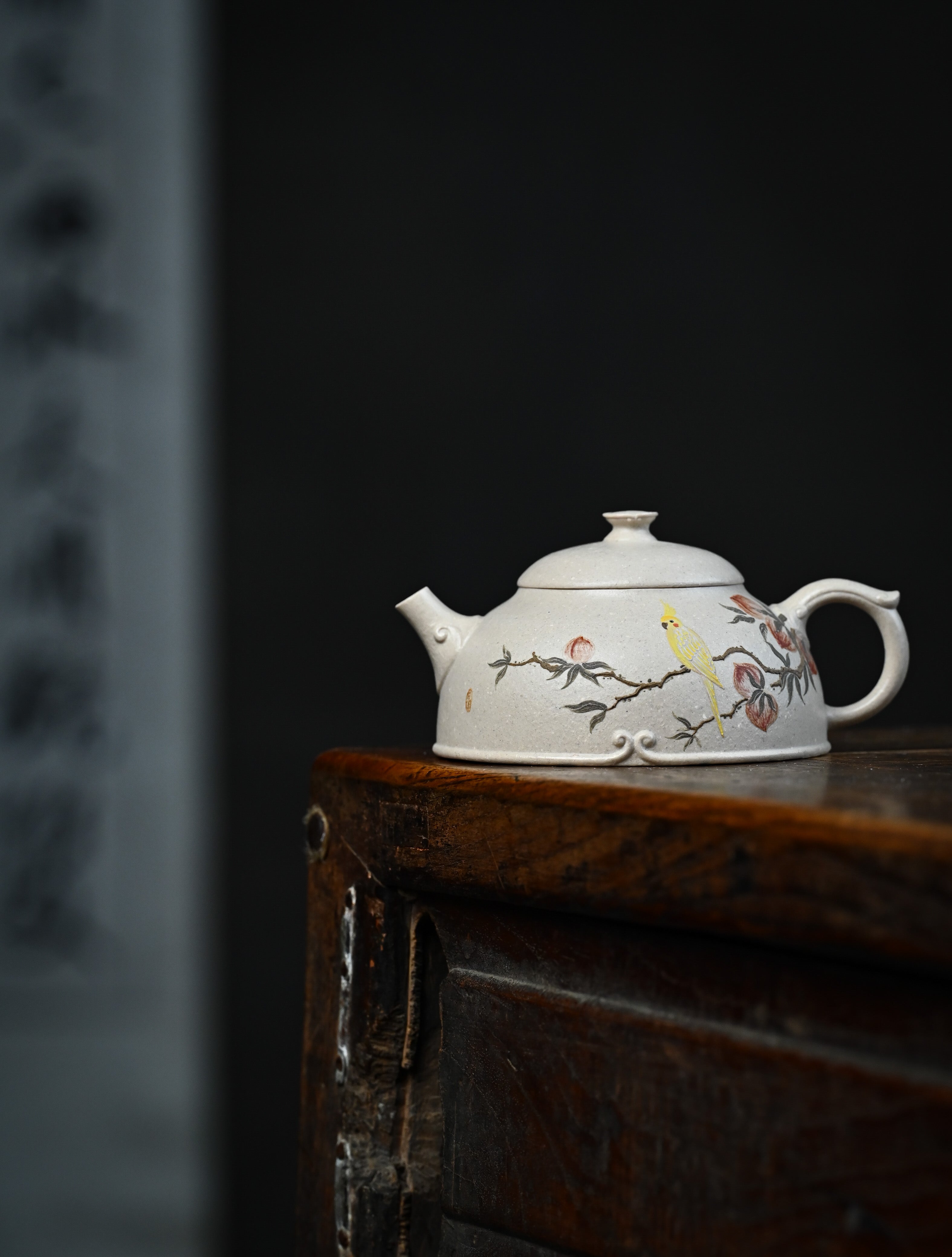 YANYOO handmade Yixing teapot featuring suet white jade Duanni clay and delicate bird-and-peach themed clay painting, lifestyle wide-angle left side.