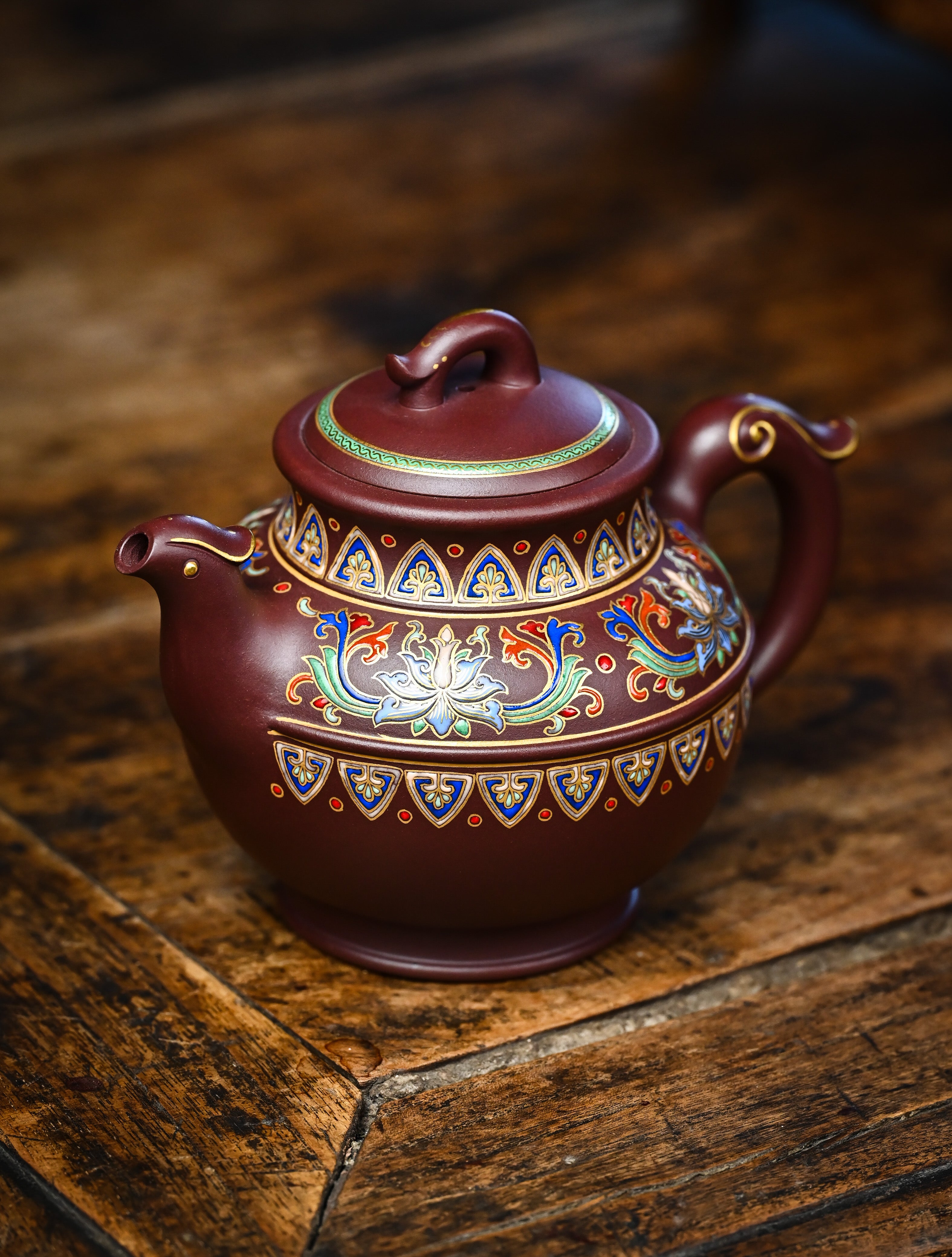 YANYOO handmade Yixing teapot featuring purple clay and lotus-themed Falangcai mimicing a phoenix, lifestyle left side.