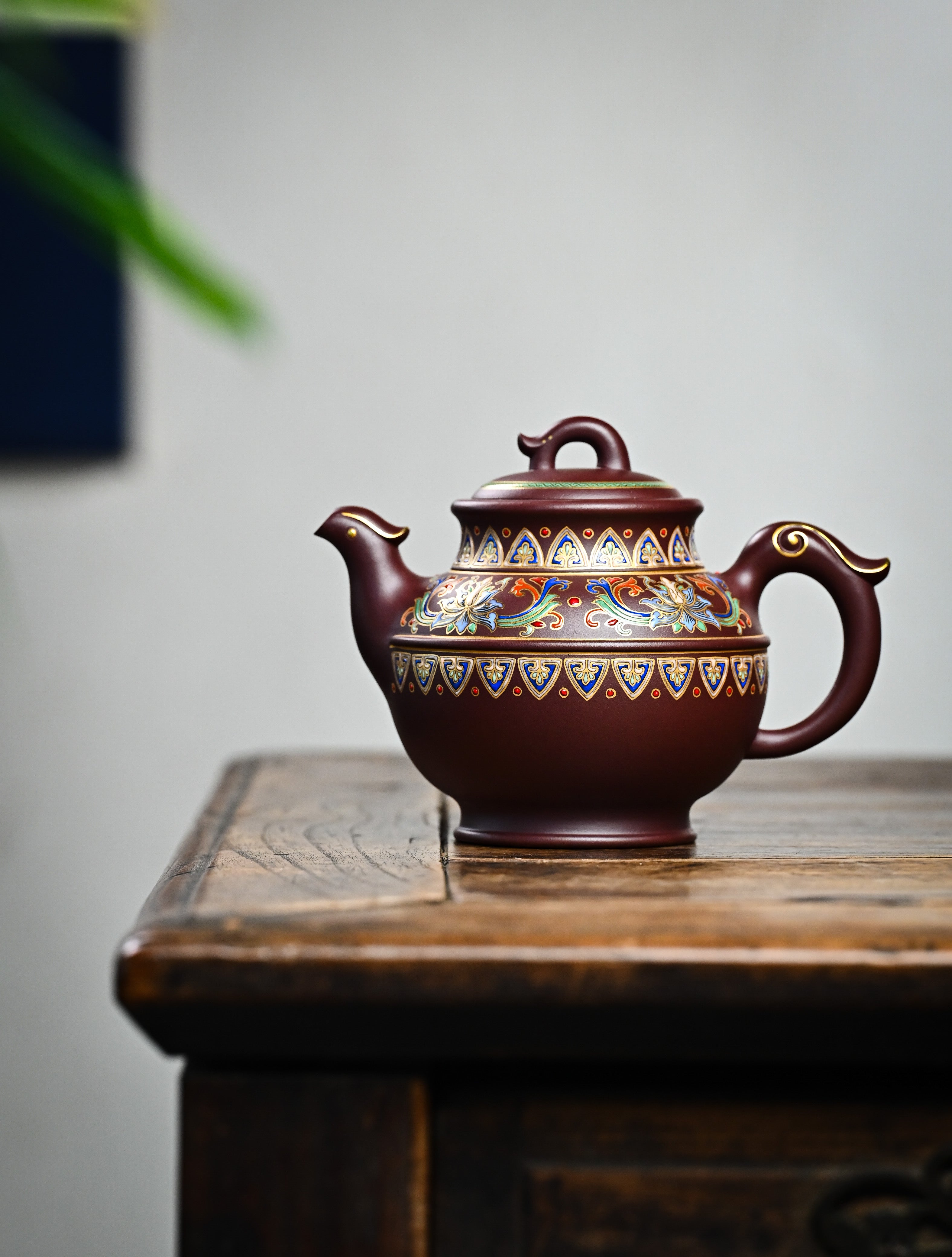 YANYOO handmade Yixing teapot featuring purple clay and lotus-themed Falangcai mimicing a phoenix, lifestyle wide-angle left side.