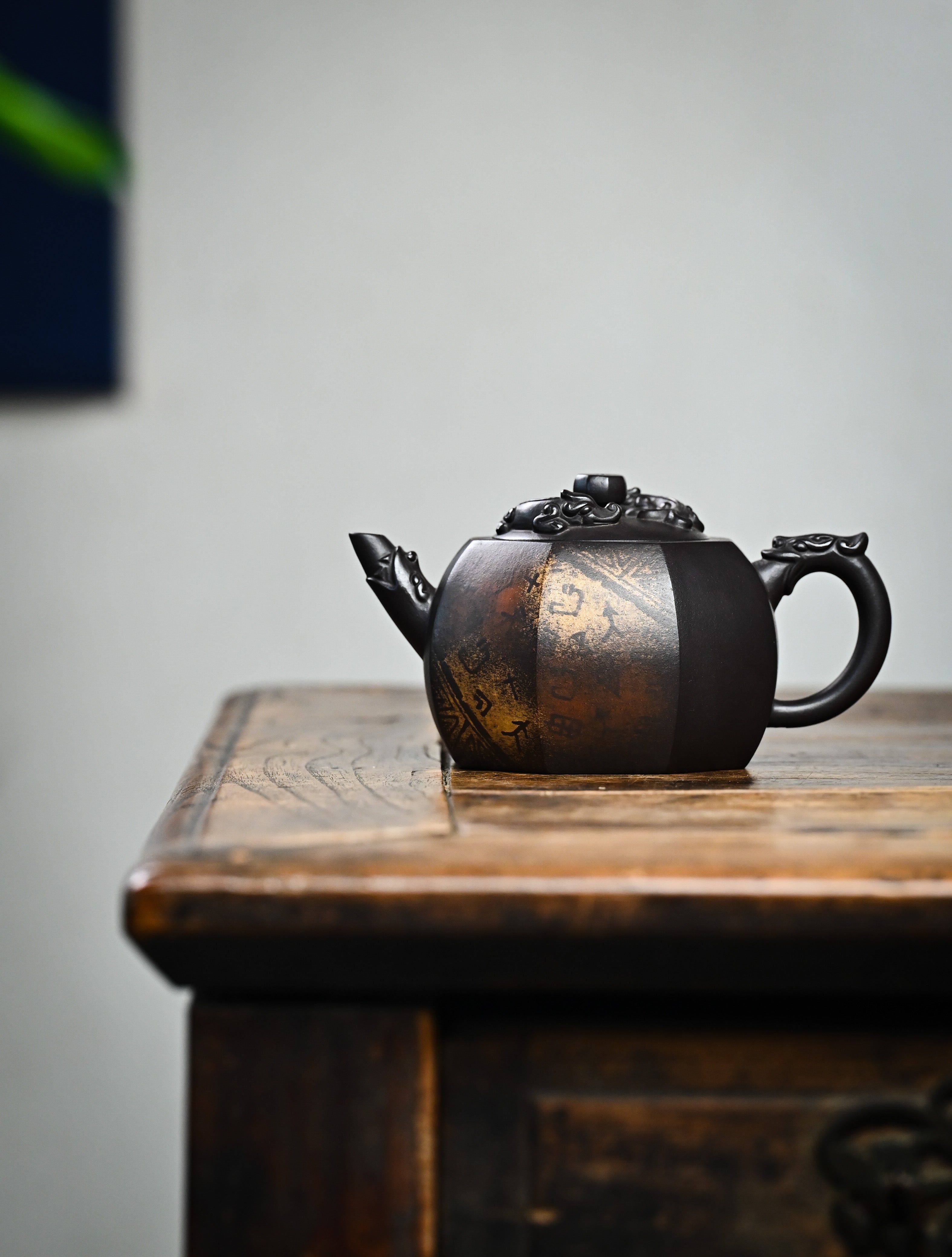 YANYOO handmade Yixing teapot featuring aged Celadon clay, Oracle Bone scripts pattern and the pioneering color decoration method, lifestyle wide-angle left side.