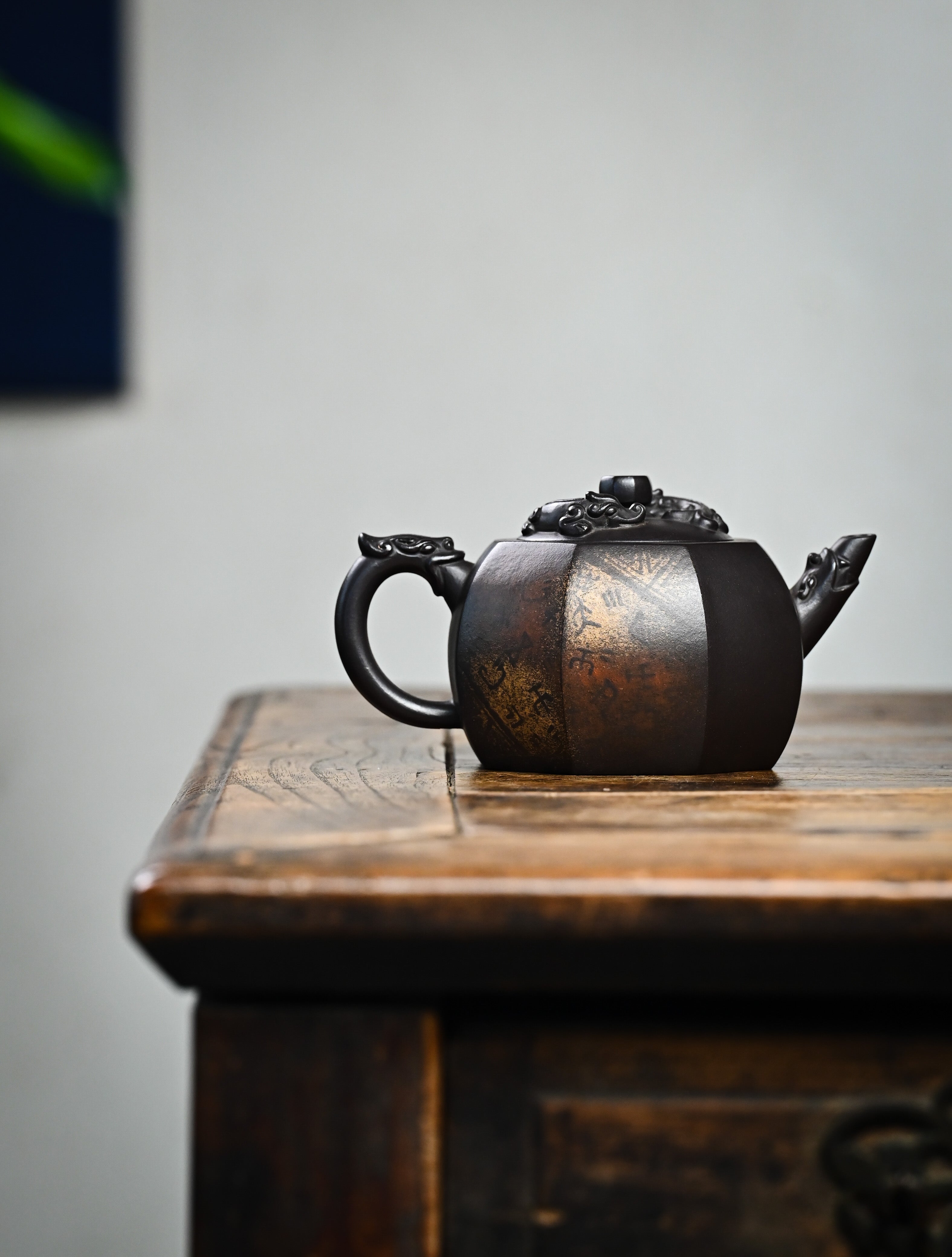 YANYOO handmade Yixing teapot featuring aged Celadon clay, Oracle Bone scripts pattern and the pioneering color decoration method, lifestyle wide-angle right side.