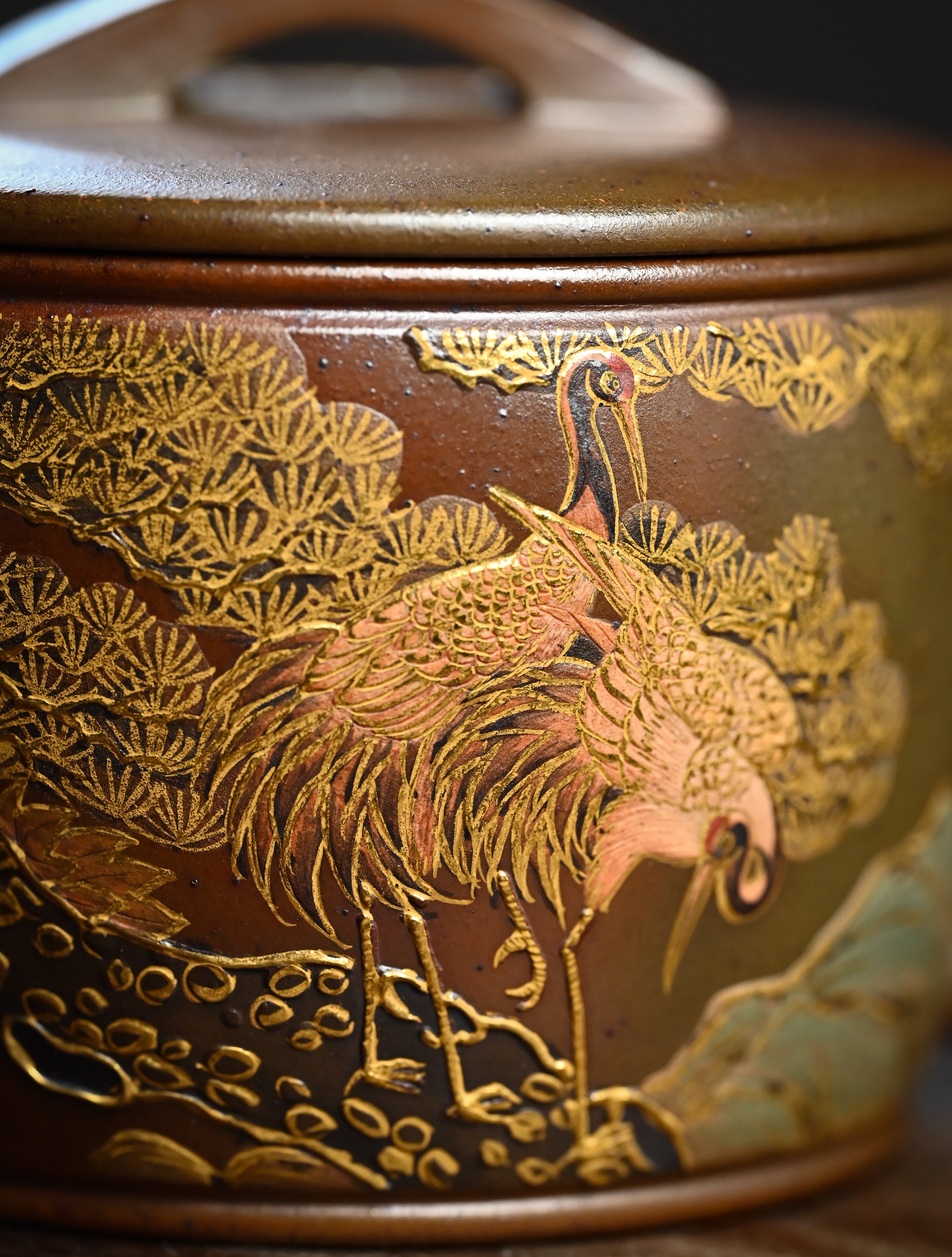 YANYOO handmade wood-fired Yixing teapot featuring hand-painted crane and gold enamel, lifestyle detail front side.