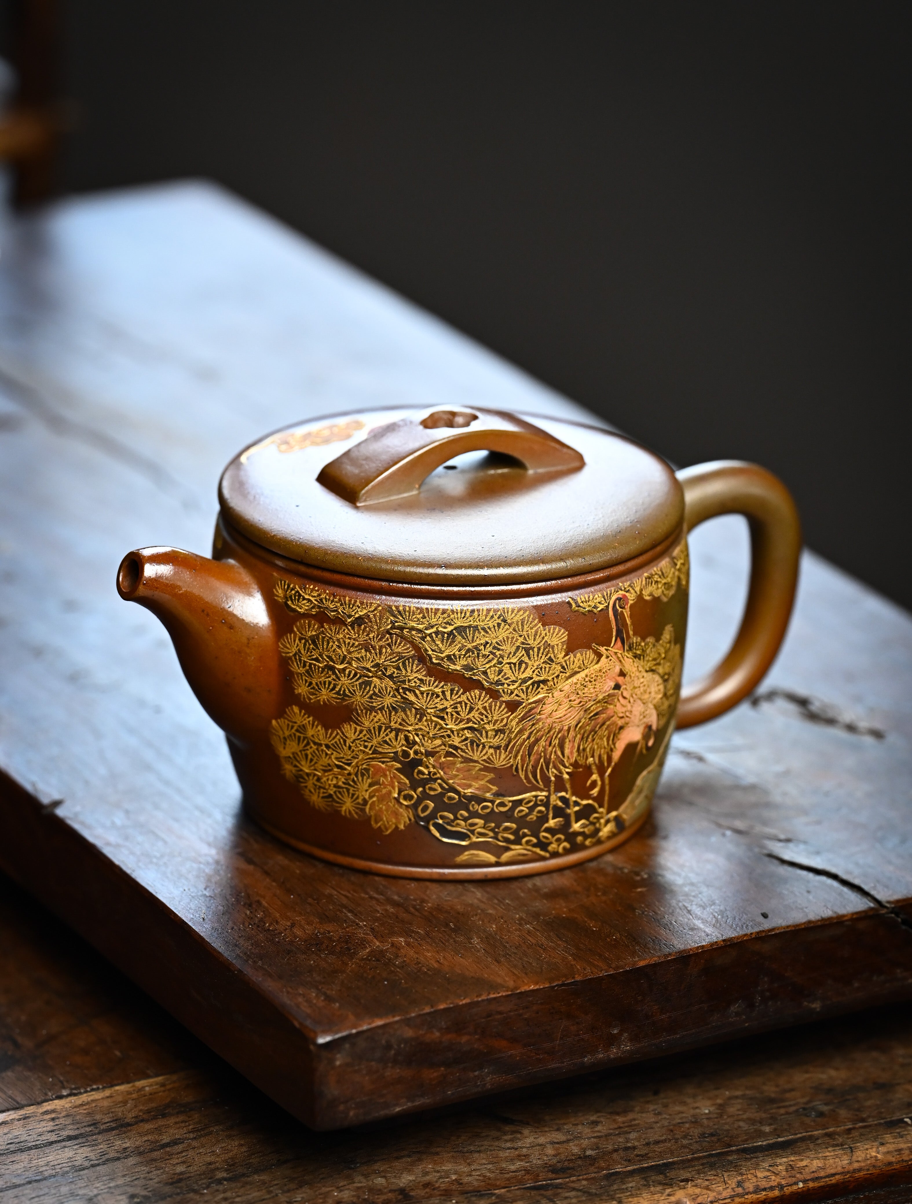 YANYOO handmade wood-fired Yixing teapot featuring hand-painted crane and gold enamel, lifestyle left side.