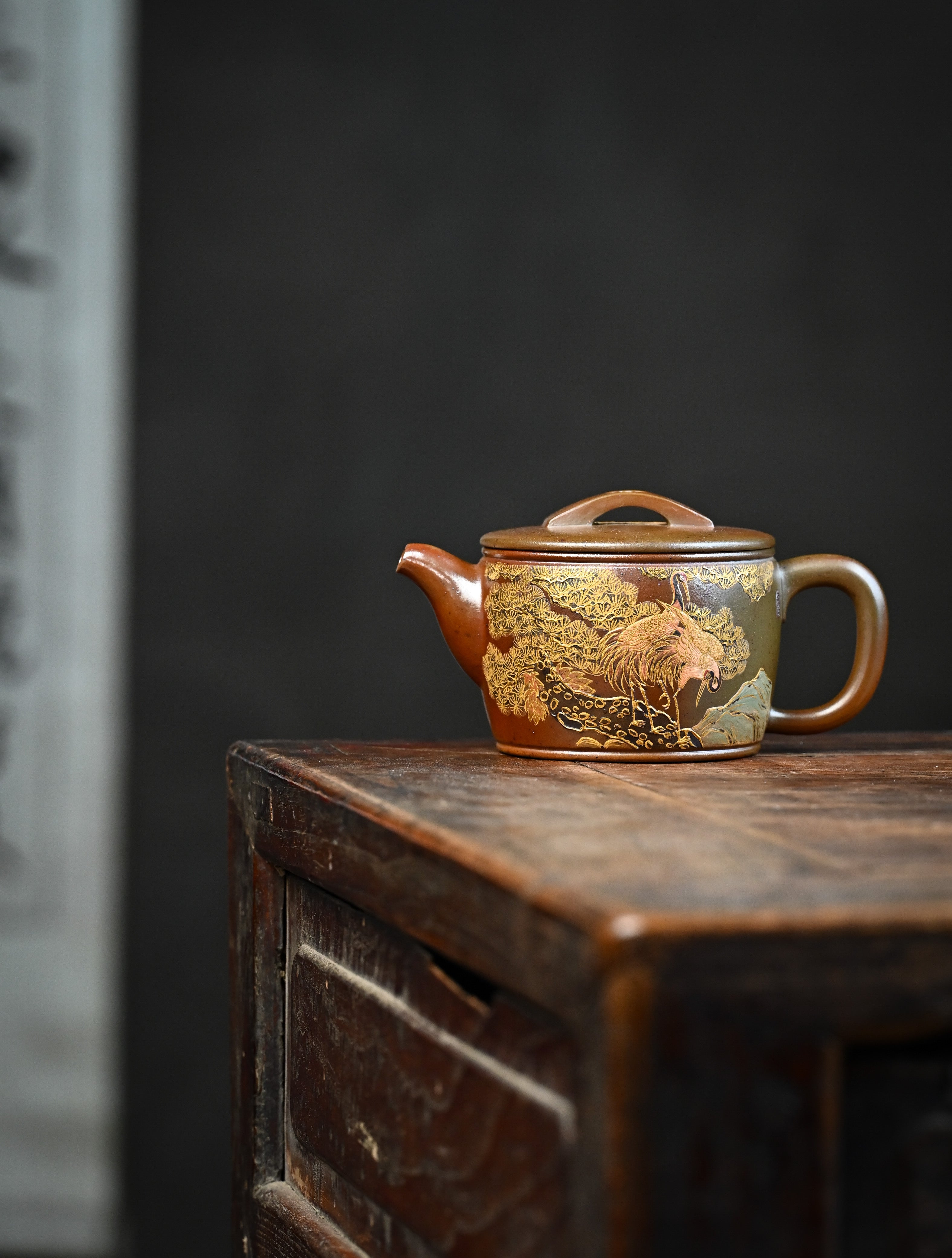 YANYOO handmade wood-fired Yixing teapot featuring hand-painted crane and gold enamel, lifestyle wide-angle left side.