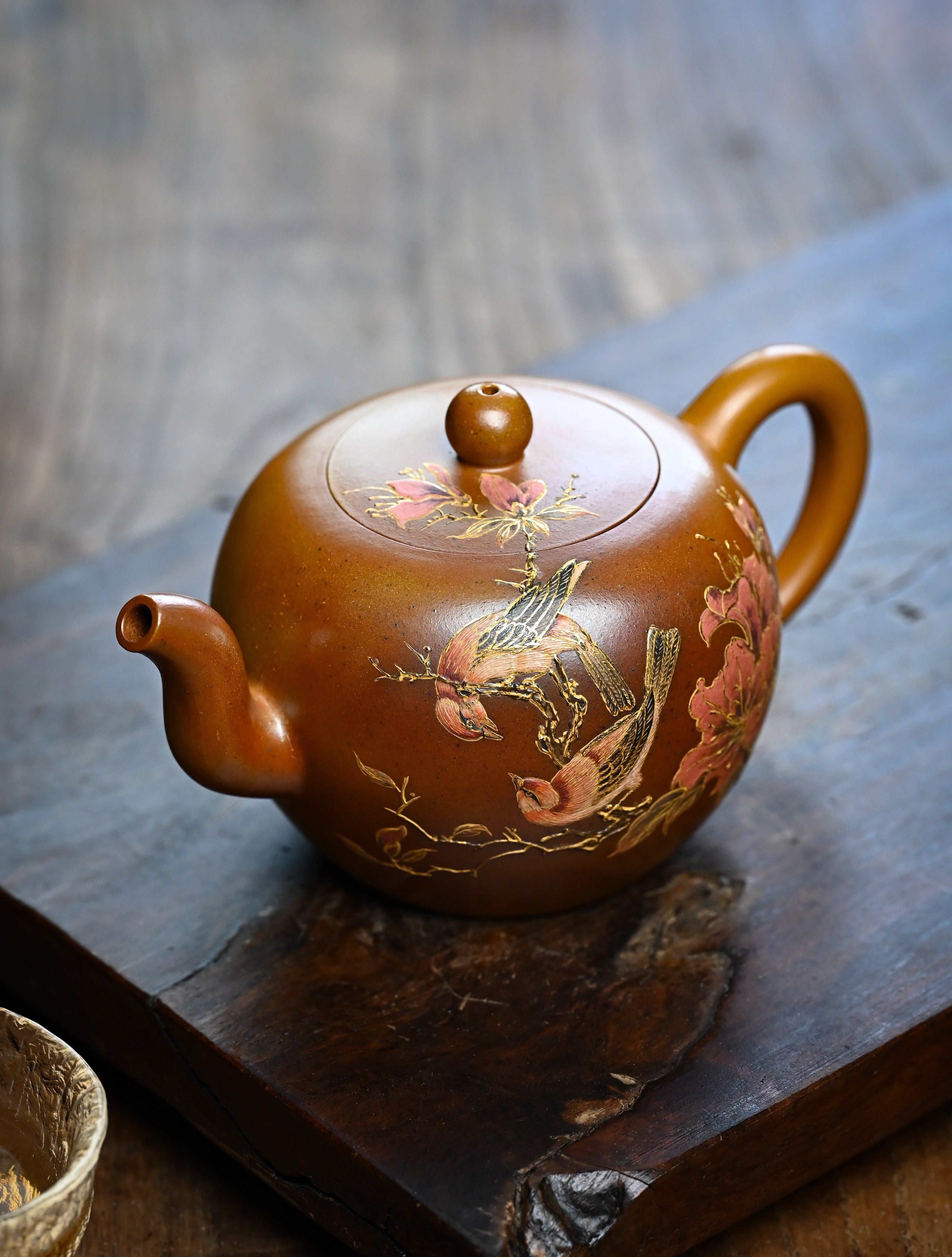 YANYOO handmade wood-fired Yixing teapot featuring hand-painted floral-and-bird motif, lifestyle left side.