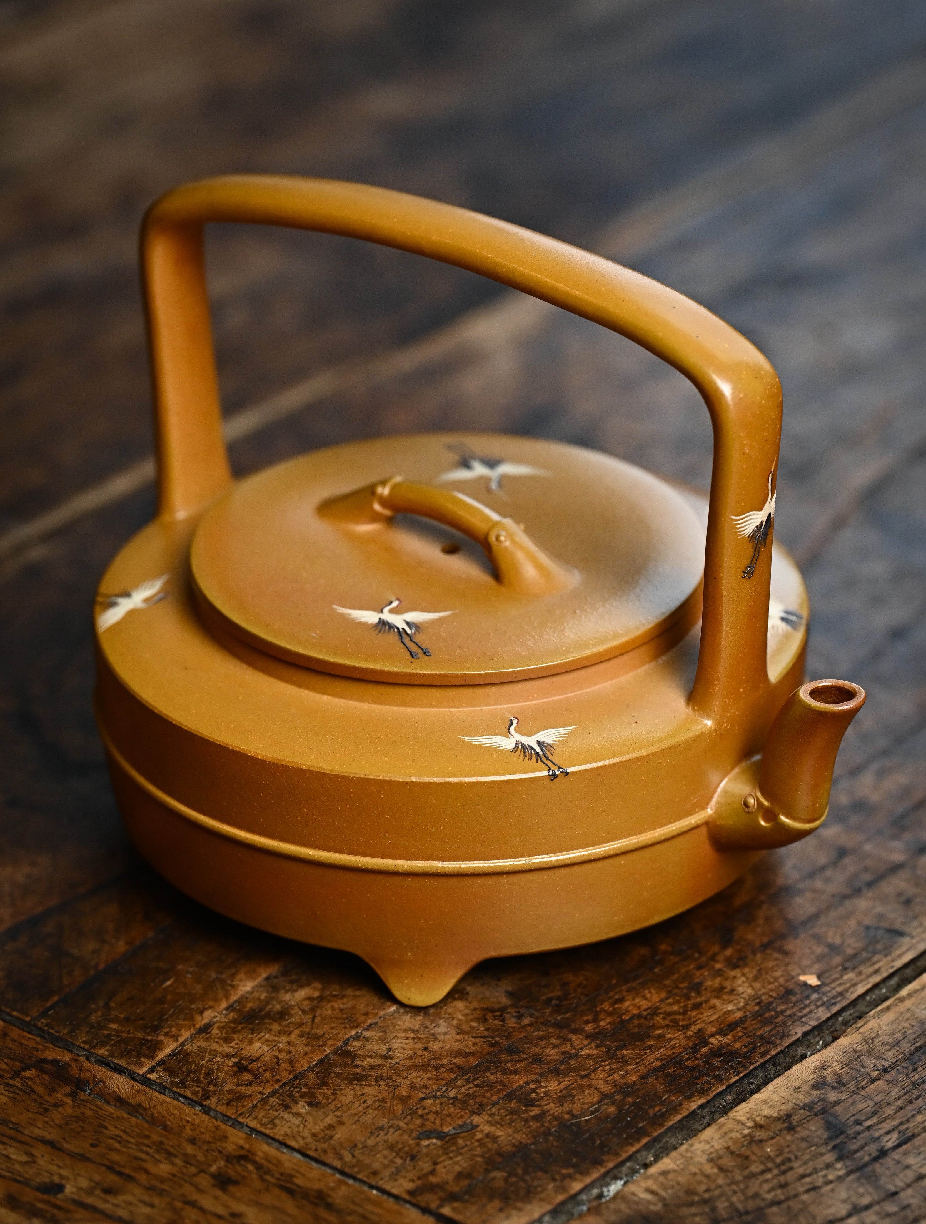 YANYOO handmade wood-fired Yixing teapot featuring hand-painted cloud-and-crane motif and lifting handle, lifestyle right side.
