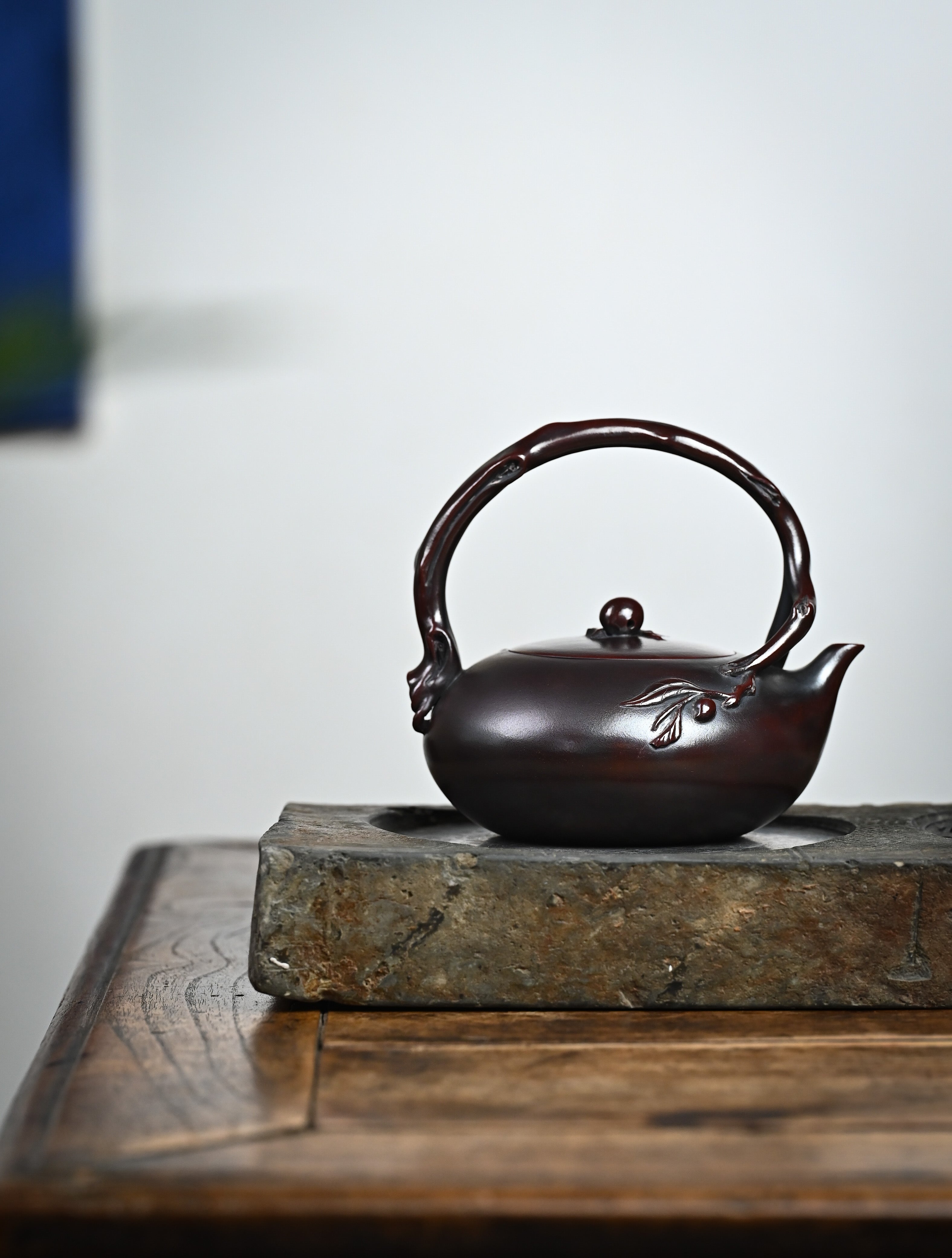 YANYOO handmade Yixing teapot featuring aged Wuni clay, lifting handle and peach sculpture, lifestyle wide-angle right side.