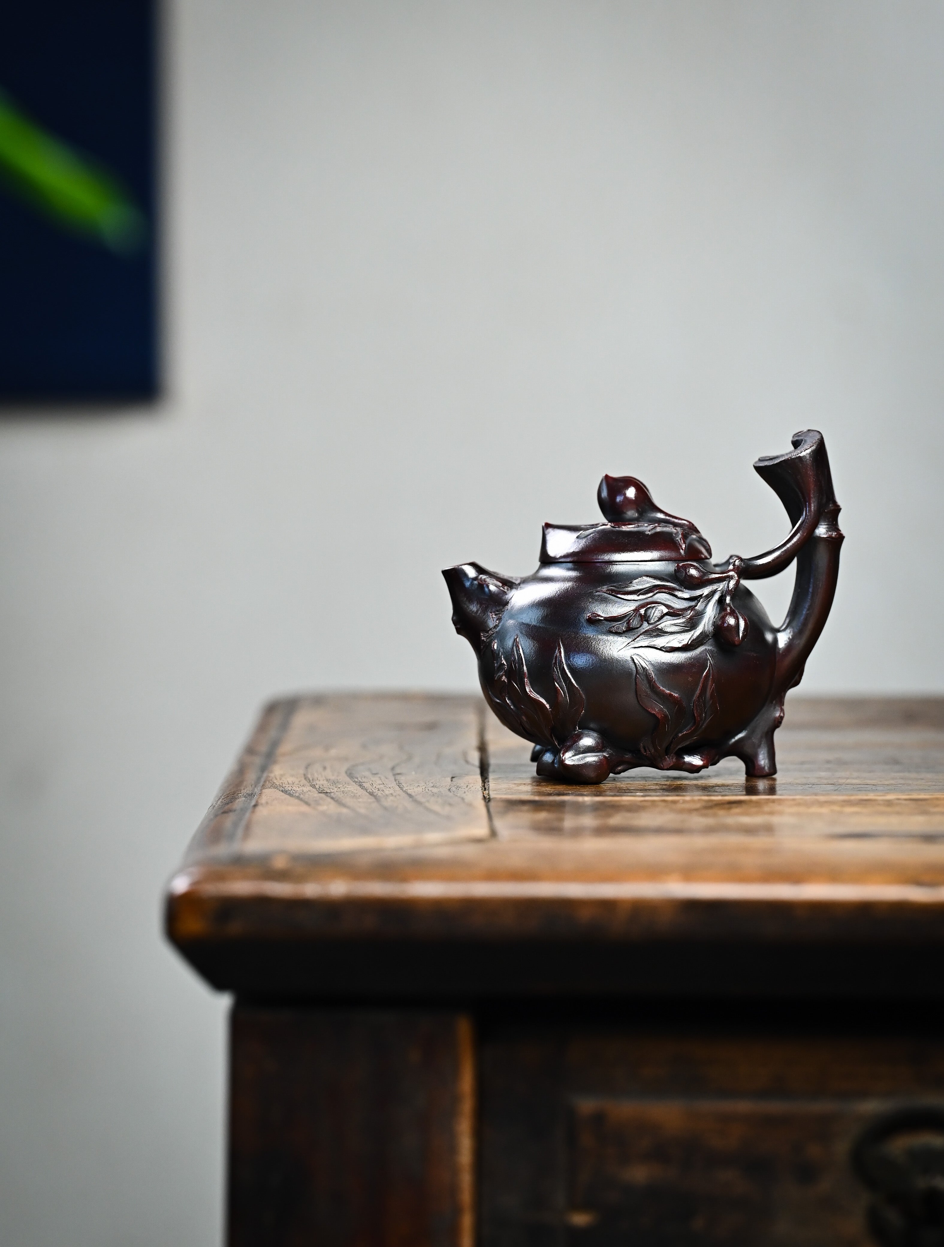 YANYOO handmade Yixing teapot featuring aged Wuni clay and peach sculpture, lifestyle wide-angle left side.