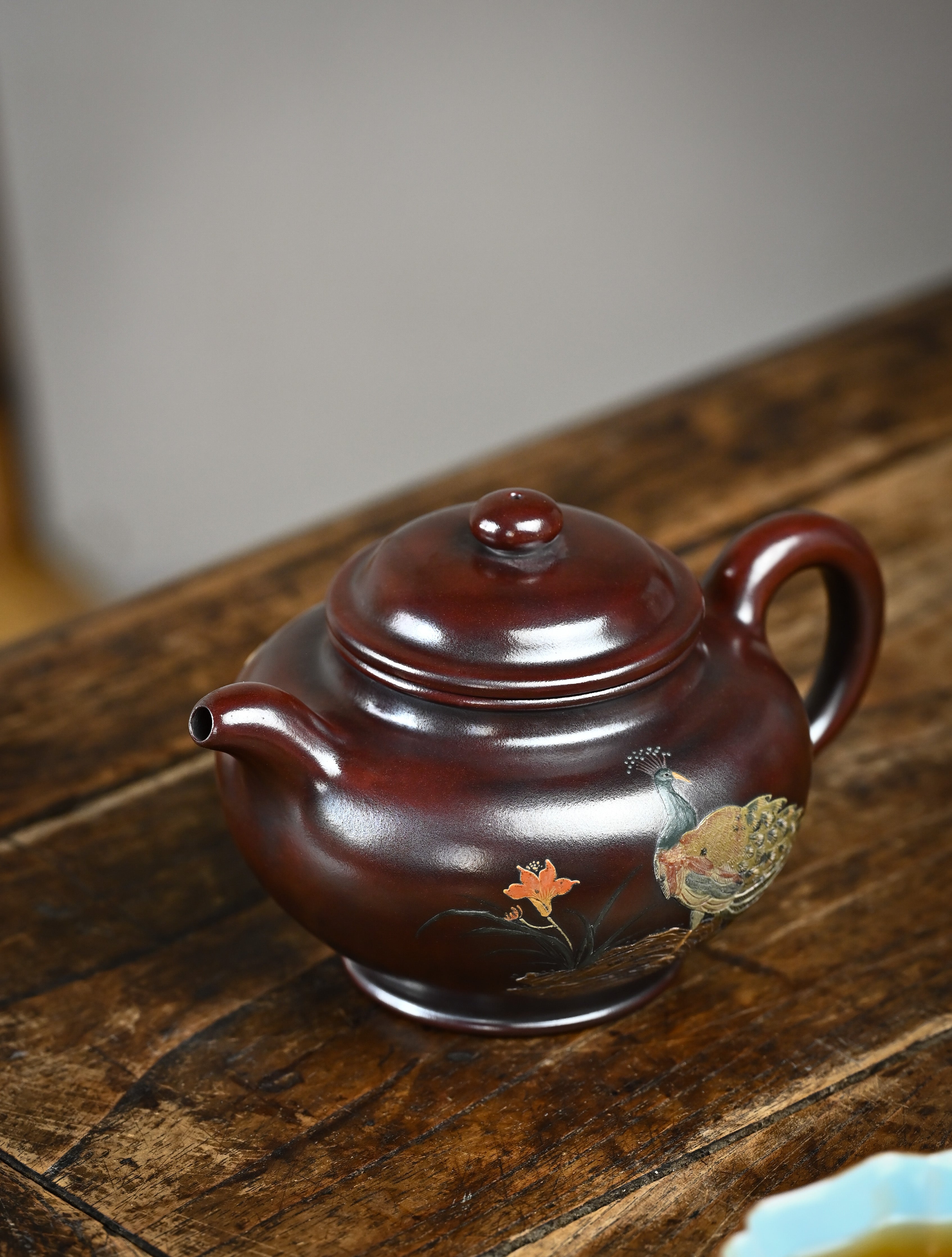 YANYOO handmade Yixing teapot featuring aged Wuni clay, peacock clay painting, Duo Zhi, lifestyle left side.