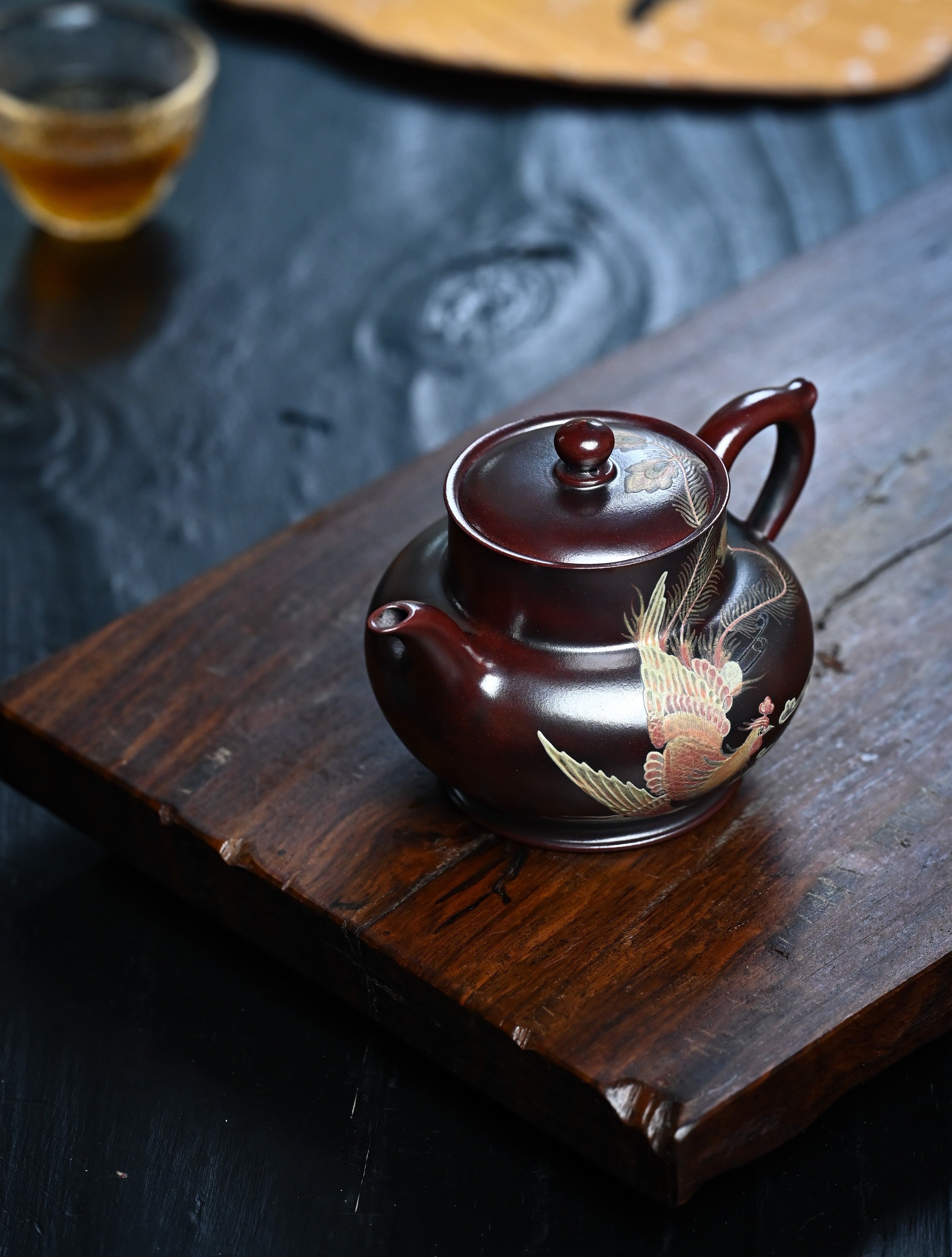 YANYOO handmade Yixing teapot featuring aged Wuni clay and phoenix-and-cloud painting, lifestyle left side.