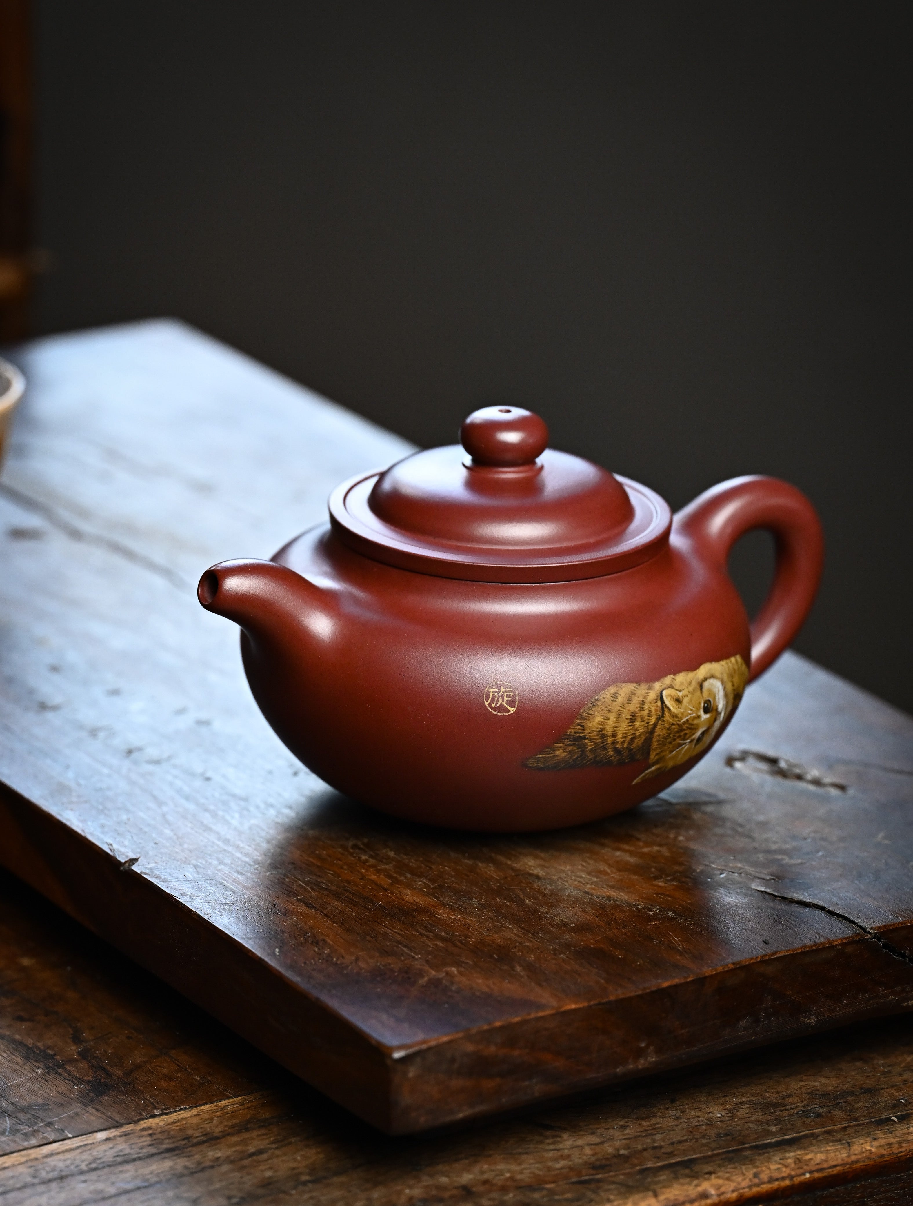 YANYOO handmade Yixing teapot featuring Hong Pi Long clay and embedded painting of cat by Master Xuanzi, lifestyle left side.