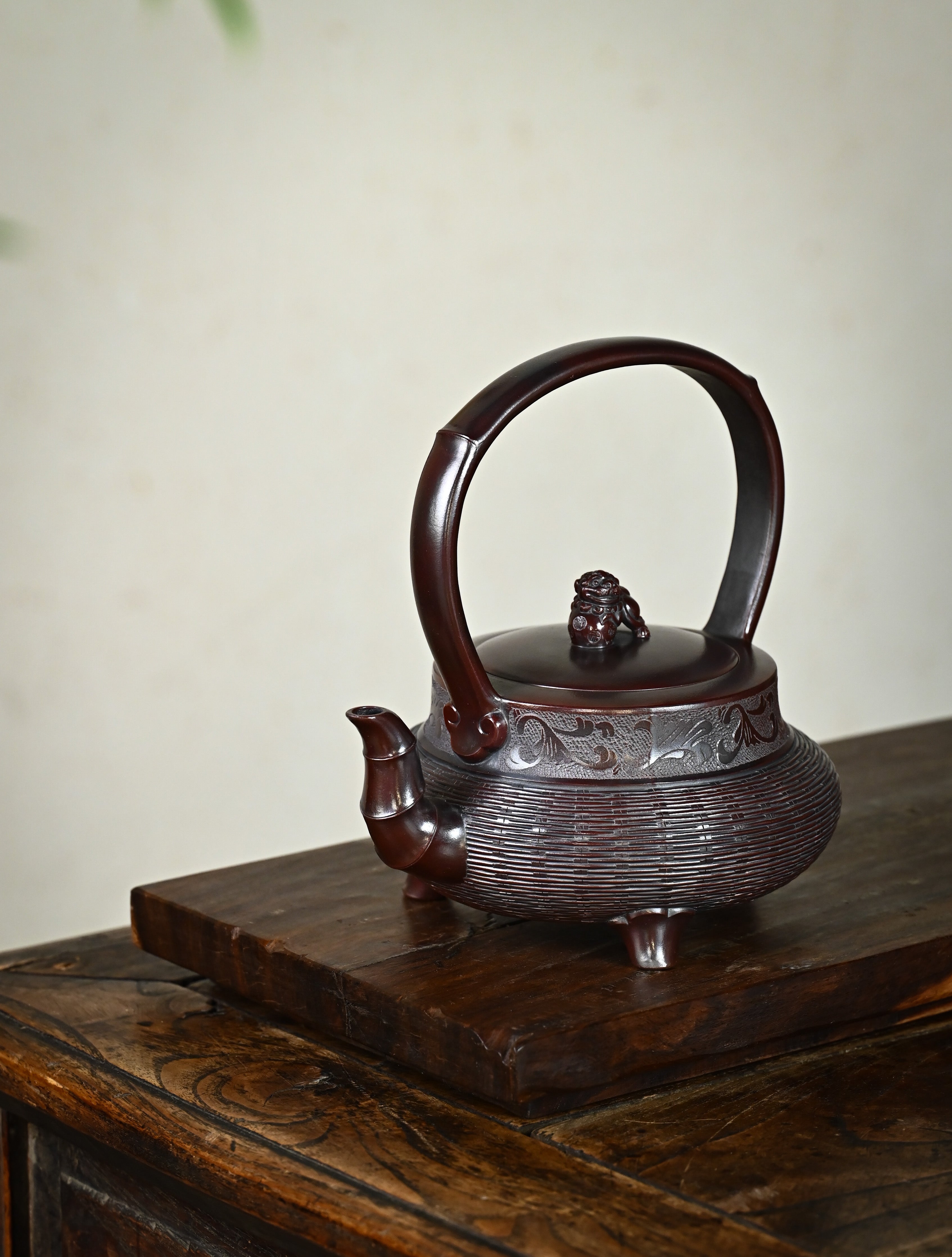 YANYOO handcrafted Yixing teapot featuring aged Wuni clay, bamboo weaving technique and delicate lifting handle, Lifting Tripod, lifestyle left side.