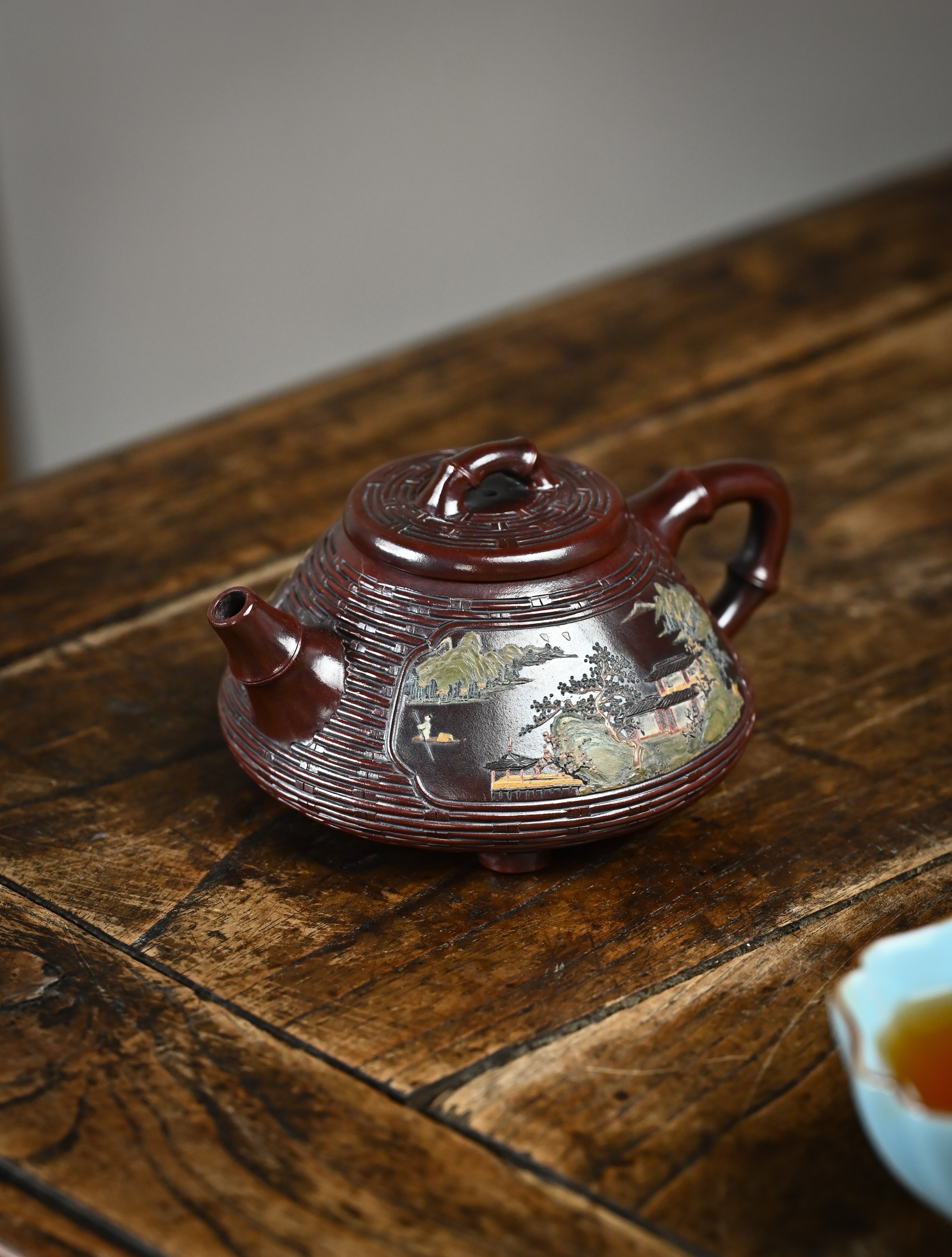 YANYOO handcrafted Yixing teapot featuring aged Wuni clay, bamboo weaving technique and exquistie hand clay painting, Shi Piao, lifestyle left side.