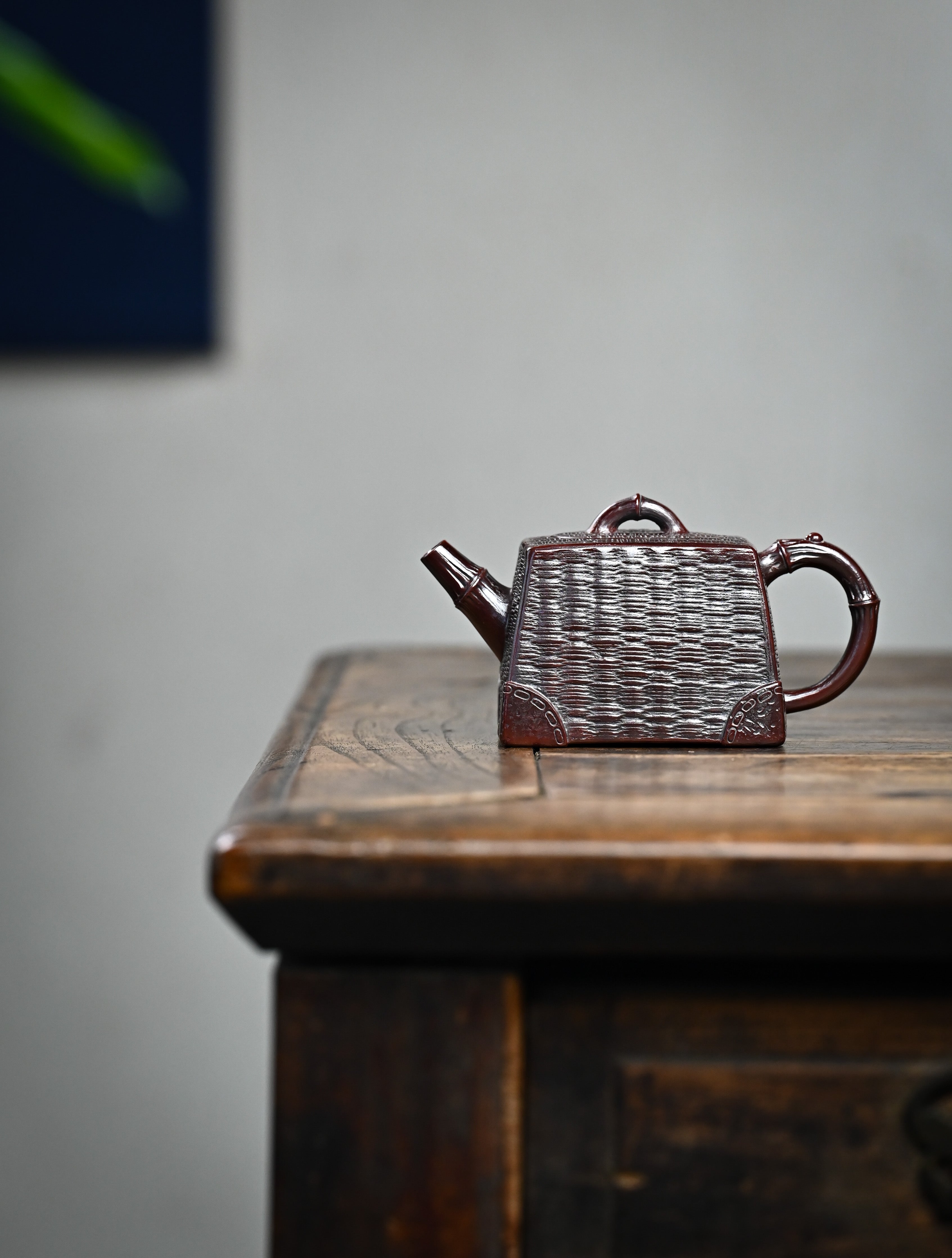 YANYOO handcrafted Yixing teapot featuring aged Wuni clay, bamboo weaving technique and a unique square shape, Si Fang, lifestyle wide-angle left side.