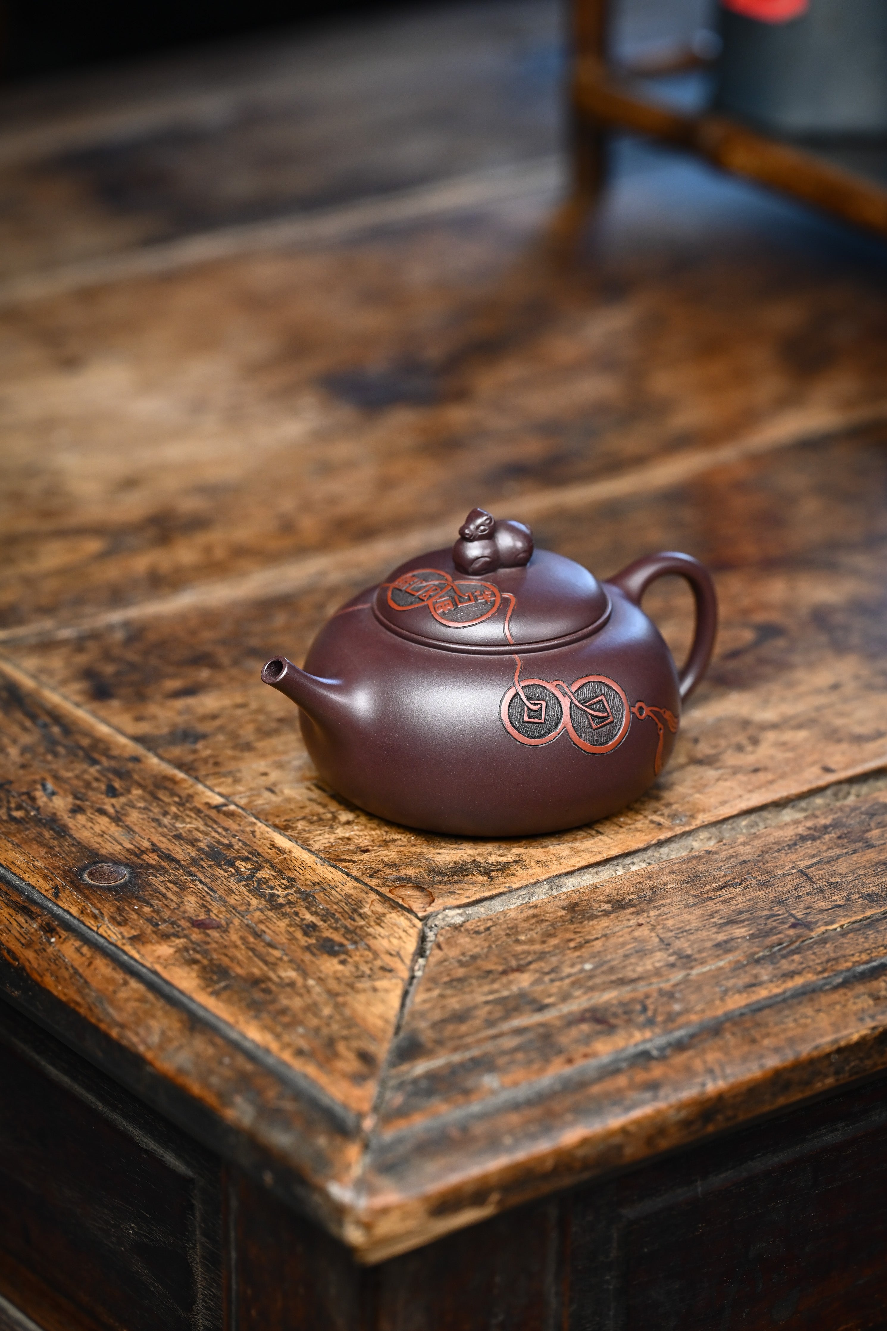 Handmade YANYOO Yixing teapot featuring Zini clay and ancient Chinese Coin sculpture, lifestyle left side.