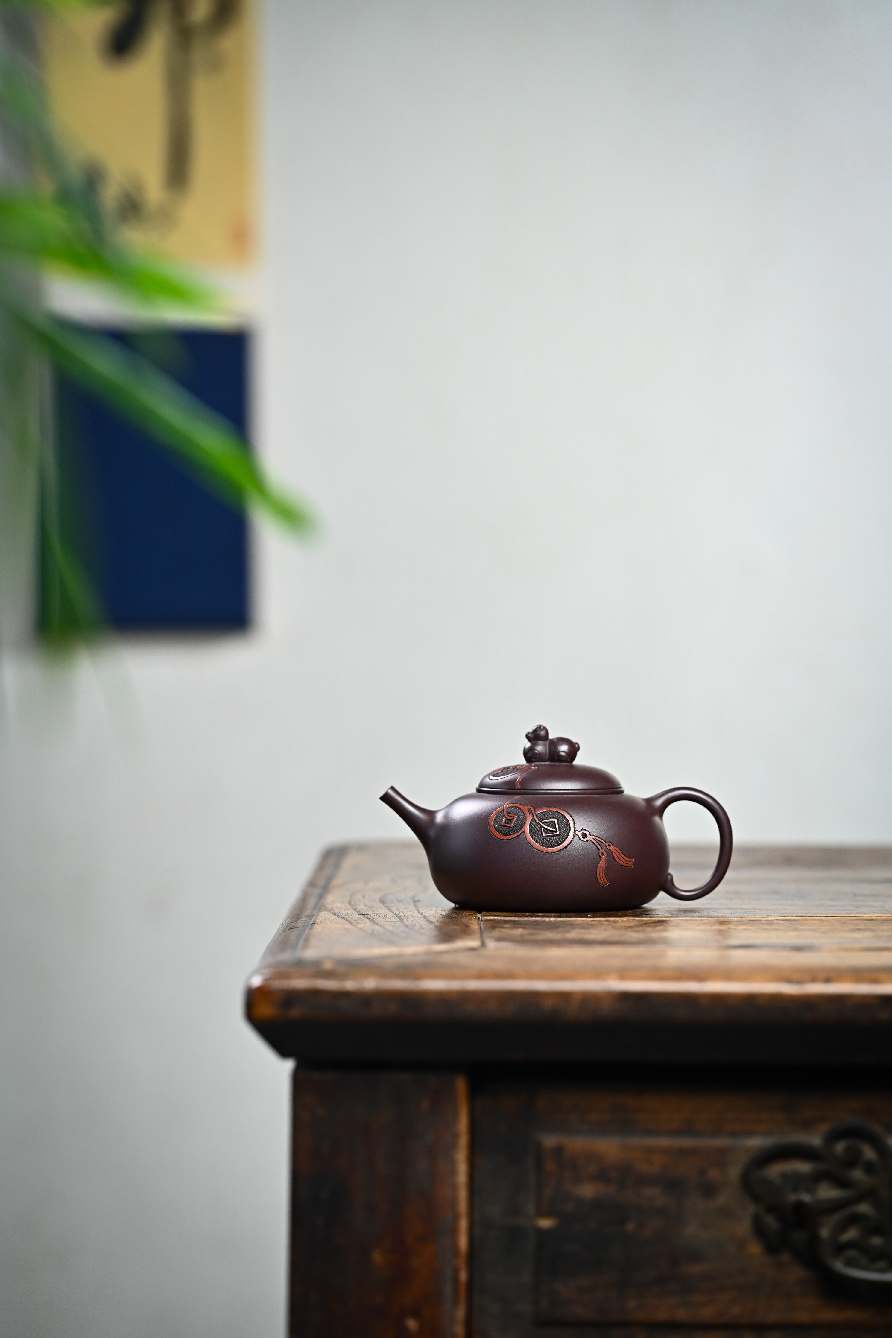 Handmade YANYOO Yixing teapot featuring Zini clay and ancient Chinese Coin sculpture, lifestyle wide-angle left side.