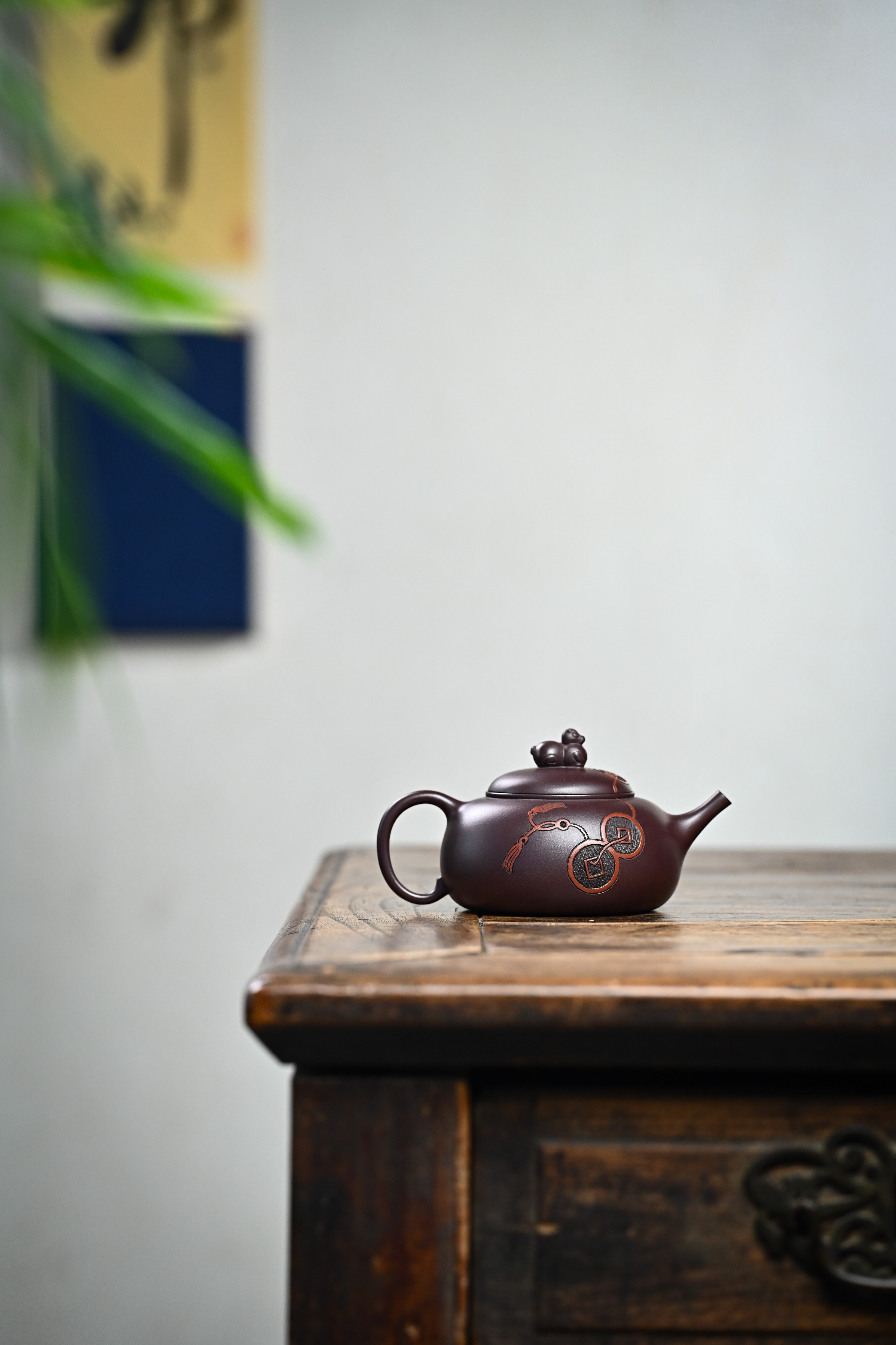 Handmade YANYOO Yixing teapot featuring Zini clay and ancient Chinese Coin sculpture, lifestyle wide-angle right side.