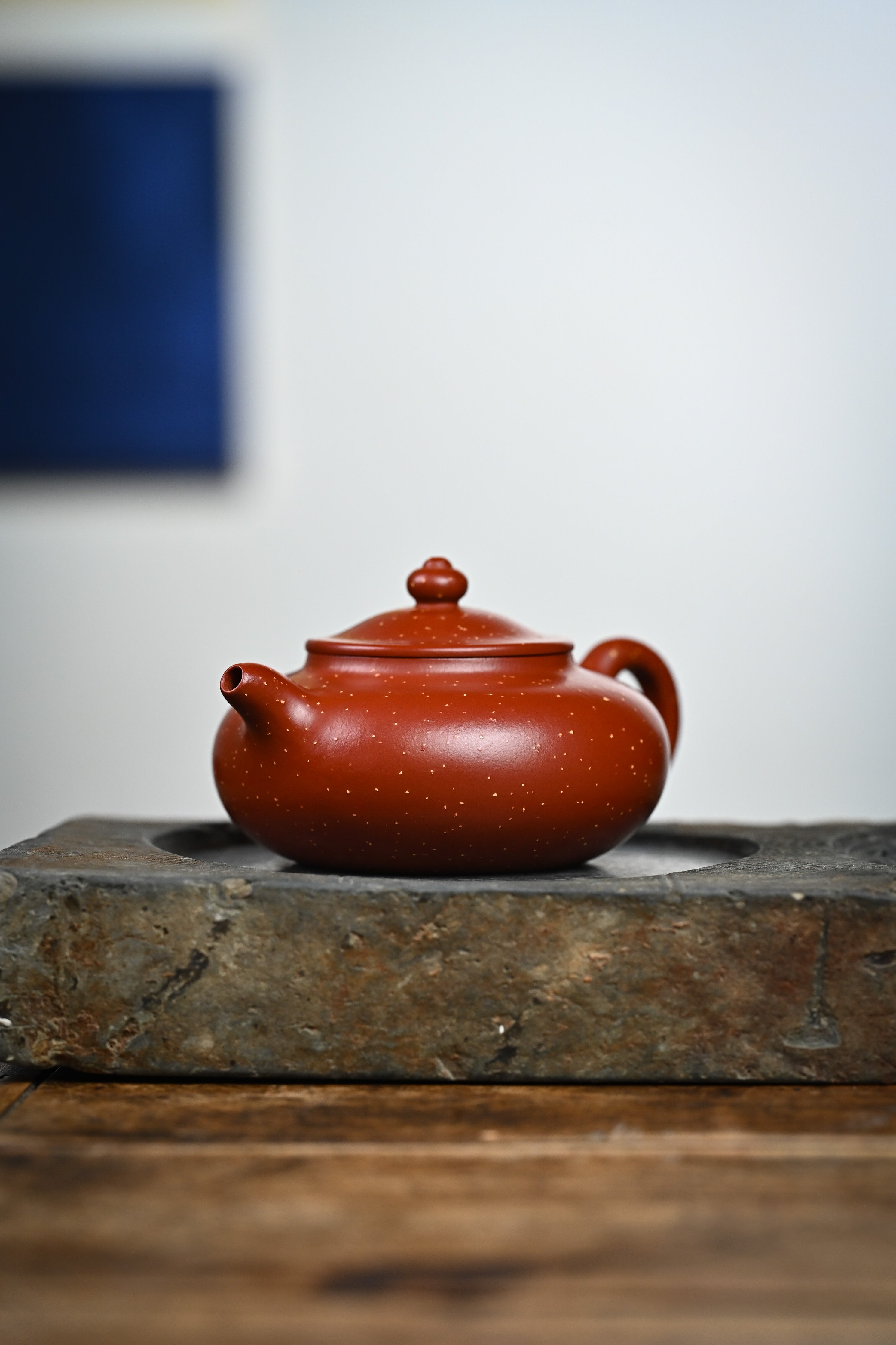 Handmade YANYOO Yixing teapot featuring Zhuni Da Hong Pao clay and sand paving technique, lifestyle front side.