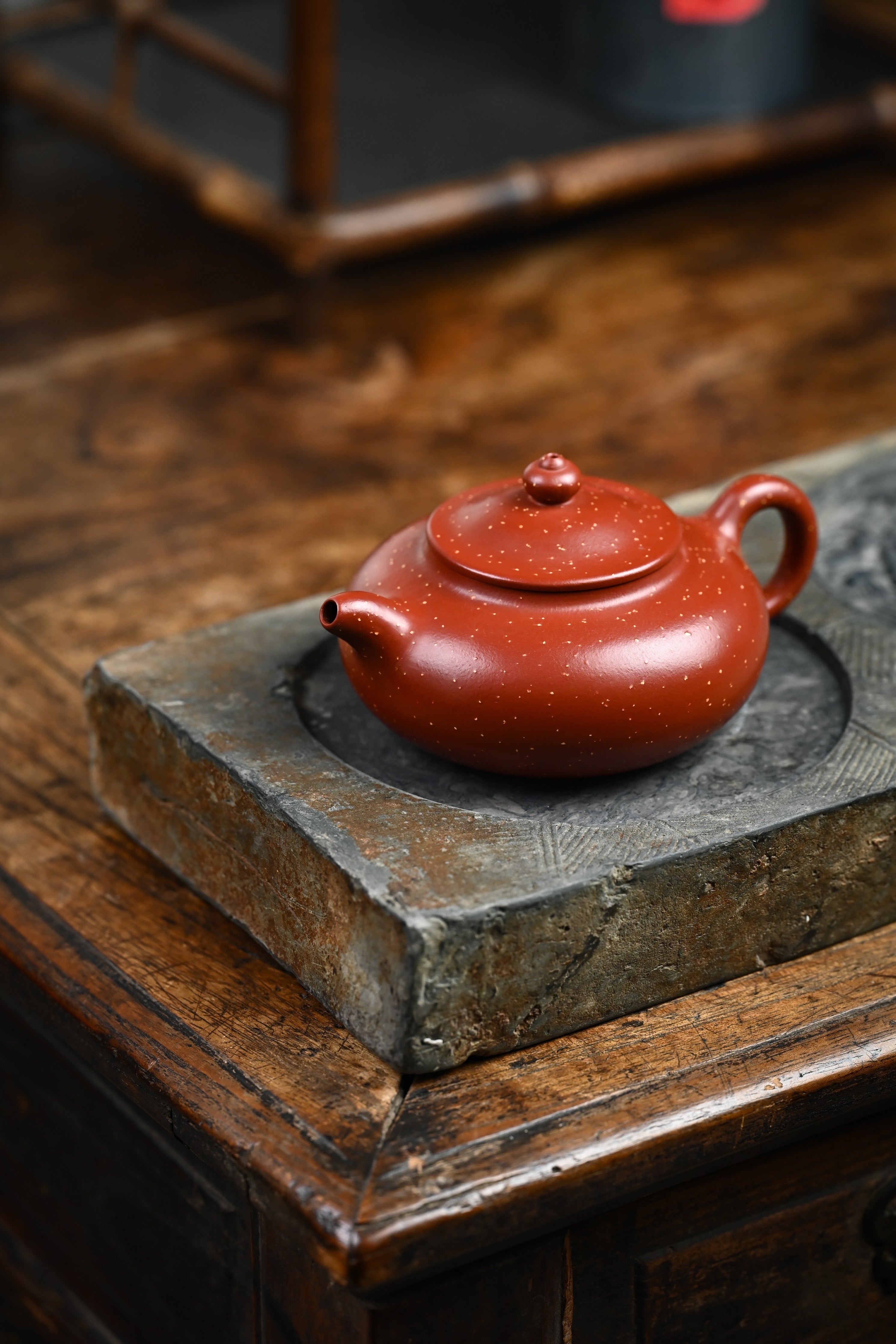 Handmade YANYOO Yixing teapot featuring Zhuni Da Hong Pao clay and sand paving technique, lifestyle left side.