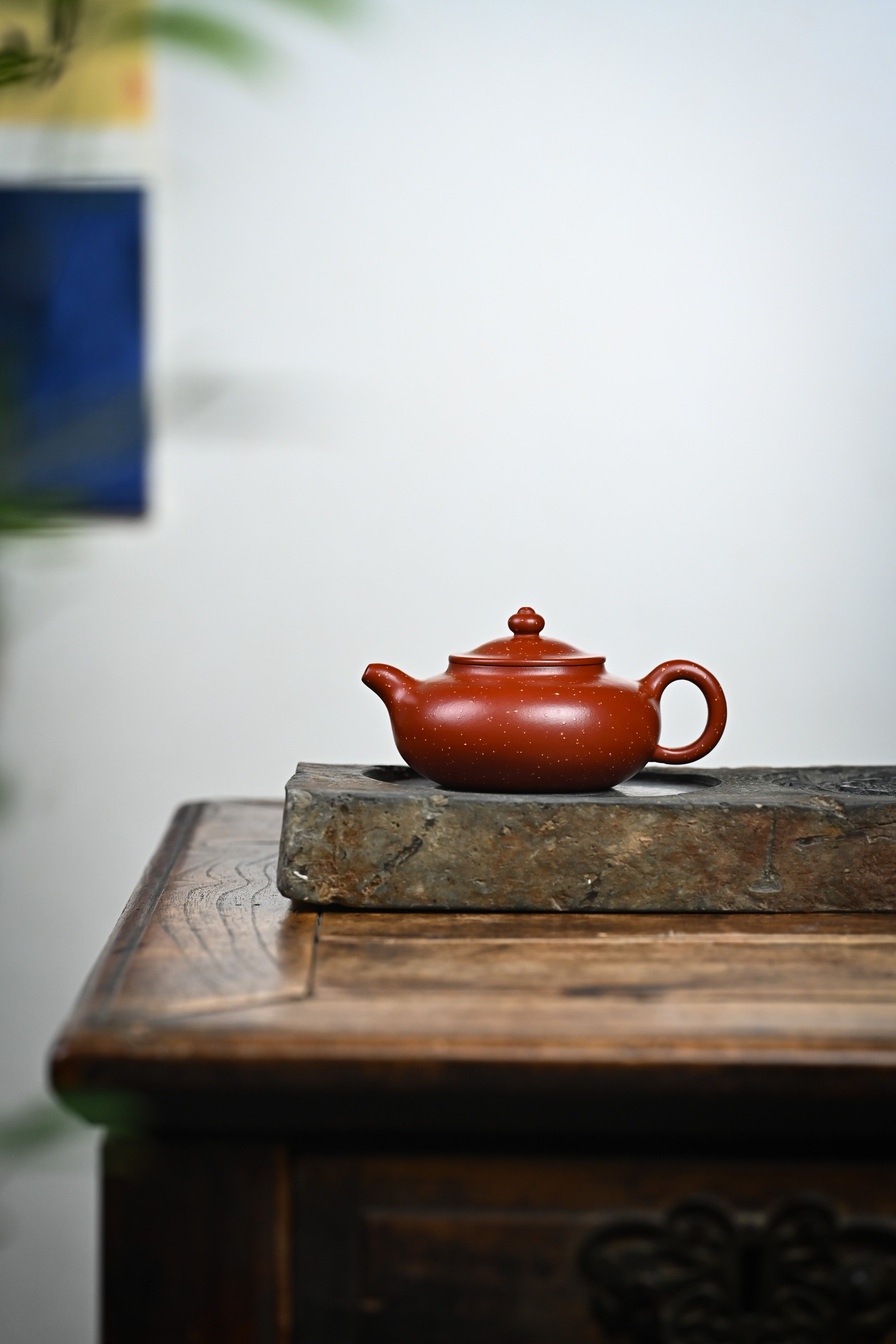 Handmade YANYOO Yixing teapot featuring Zhuni Da Hong Pao clay and sand paving technique, lifestyle wide-angle left side.