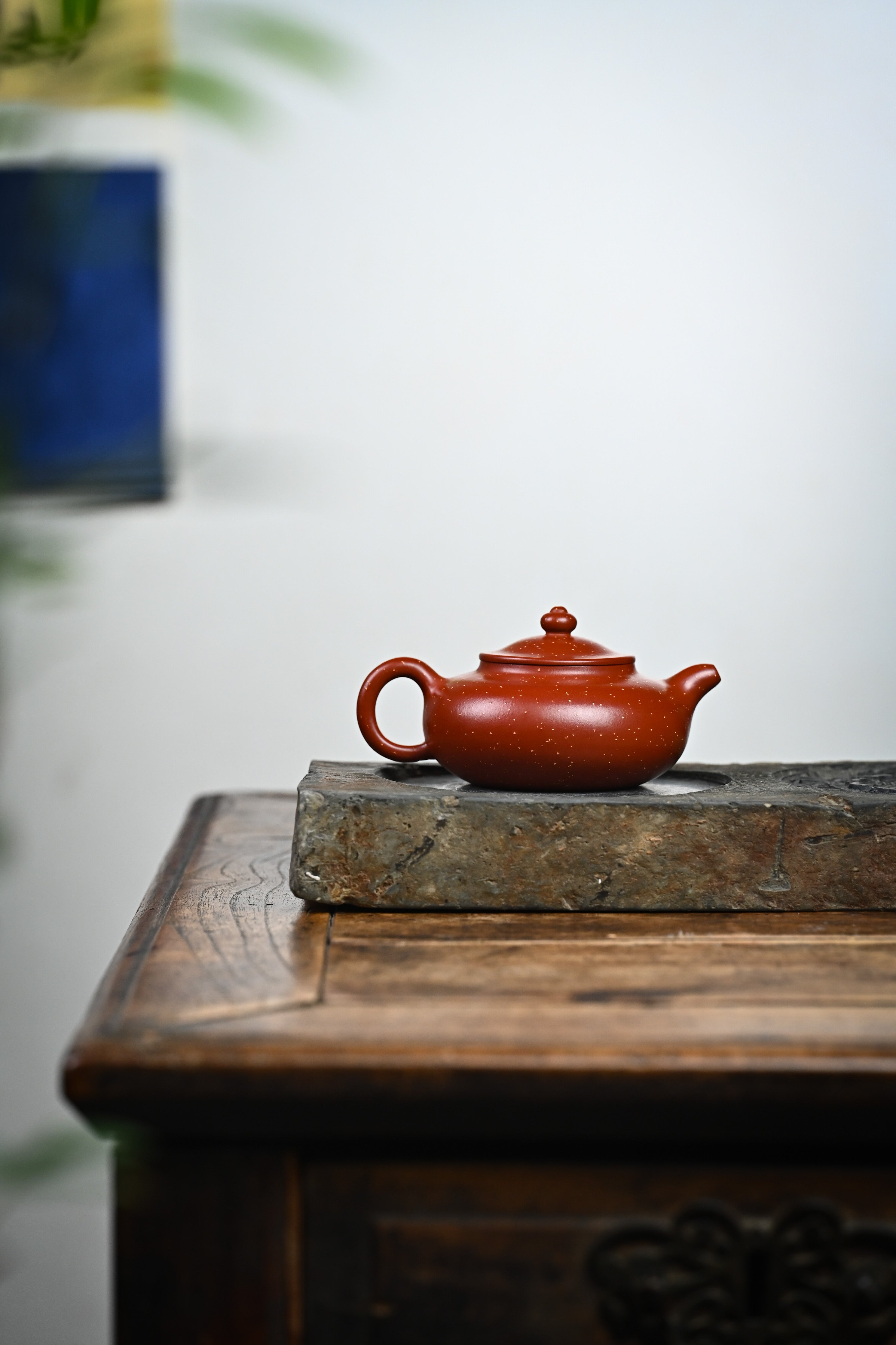 Handmade YANYOO Yixing teapot featuring Zhuni Da Hong Pao clay and sand paving technique, lifestyle wide-angle right side.