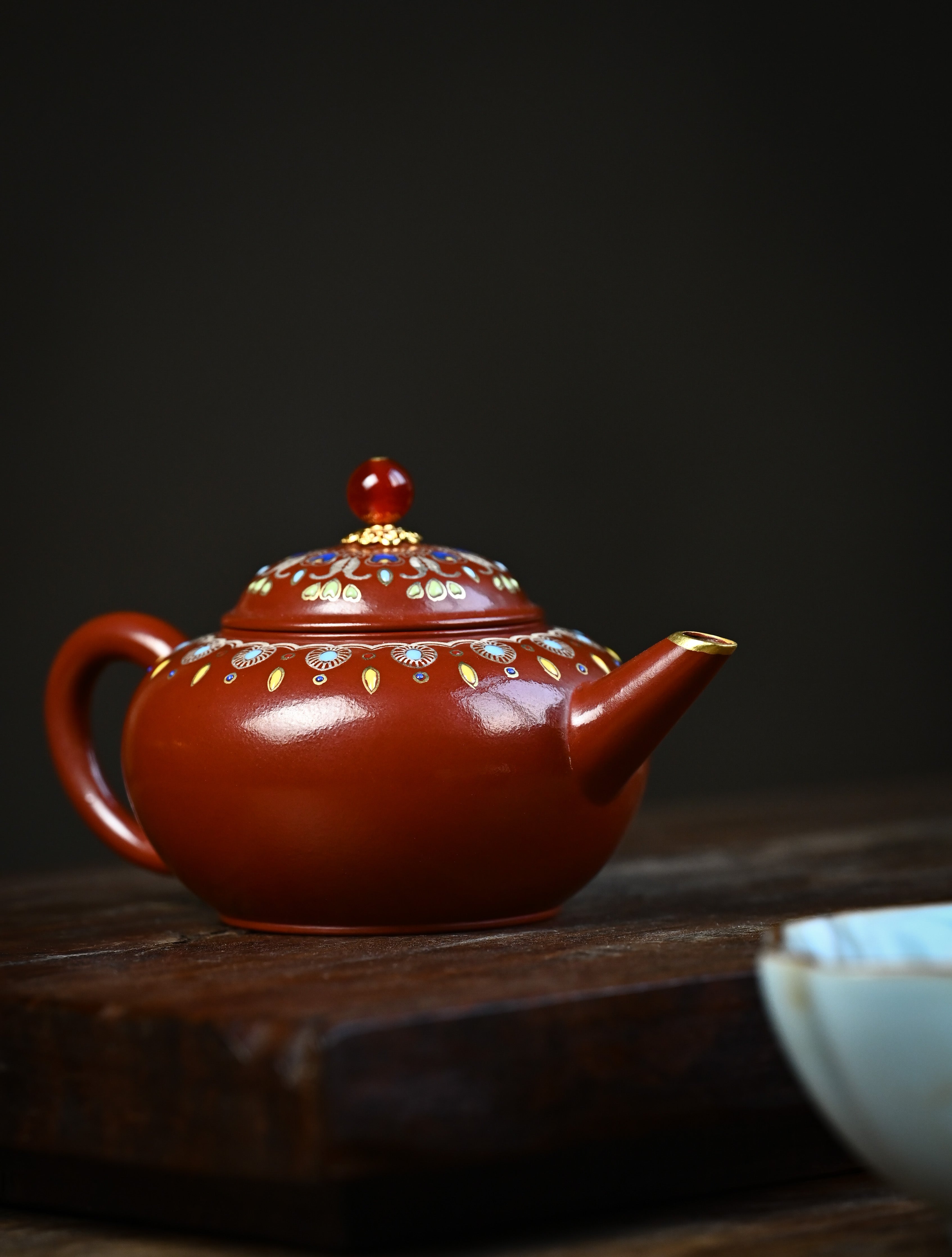 YANYOO handmade Yixing teapot featuring Zhuni clay, water polish technique (Shuimo) and delicate Falangcai, lifestyle front side.