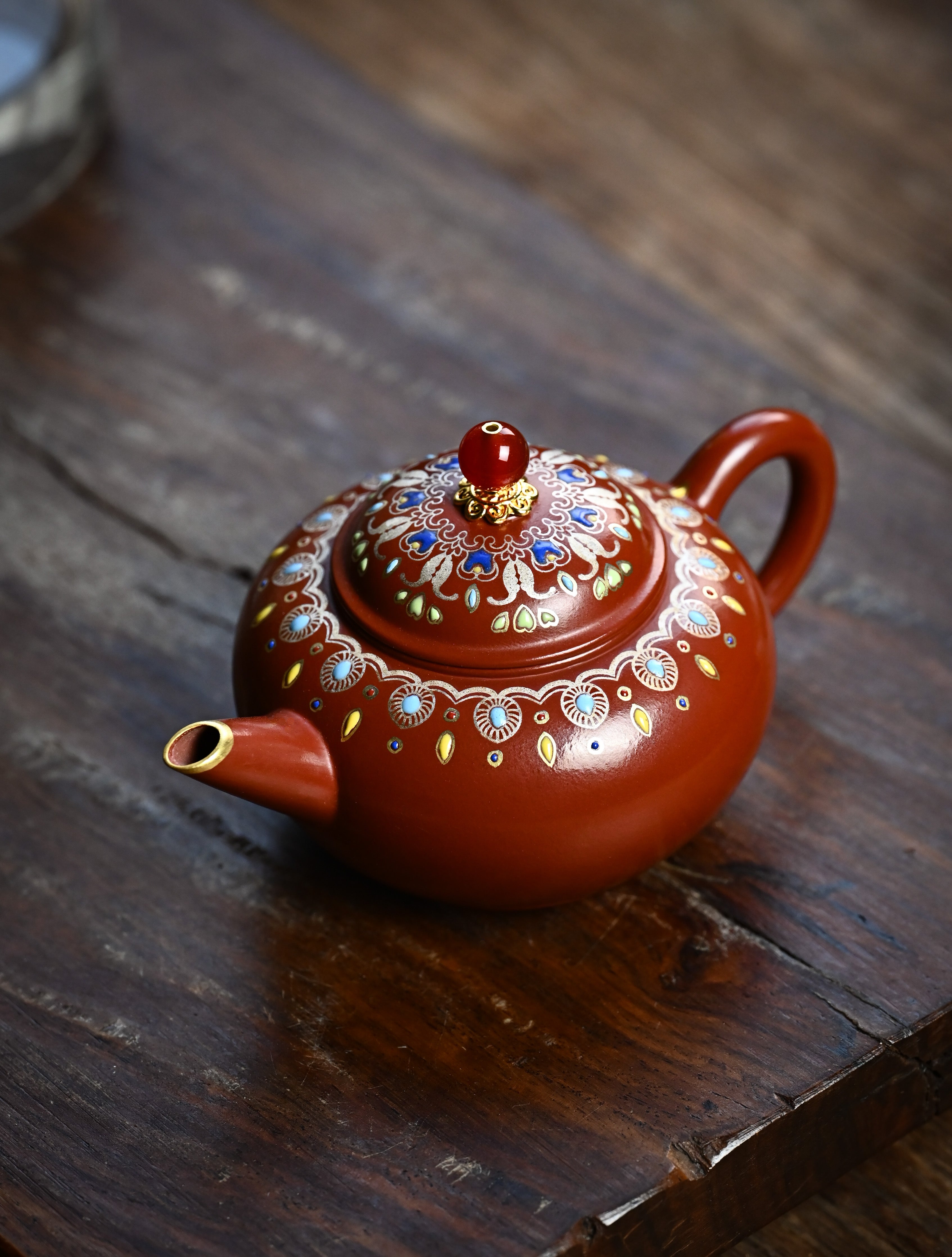 YANYOO handmade Yixing teapot featuring Zhuni clay, water polish technique (Shuimo) and delicate Falangcai, lifestyle left side.