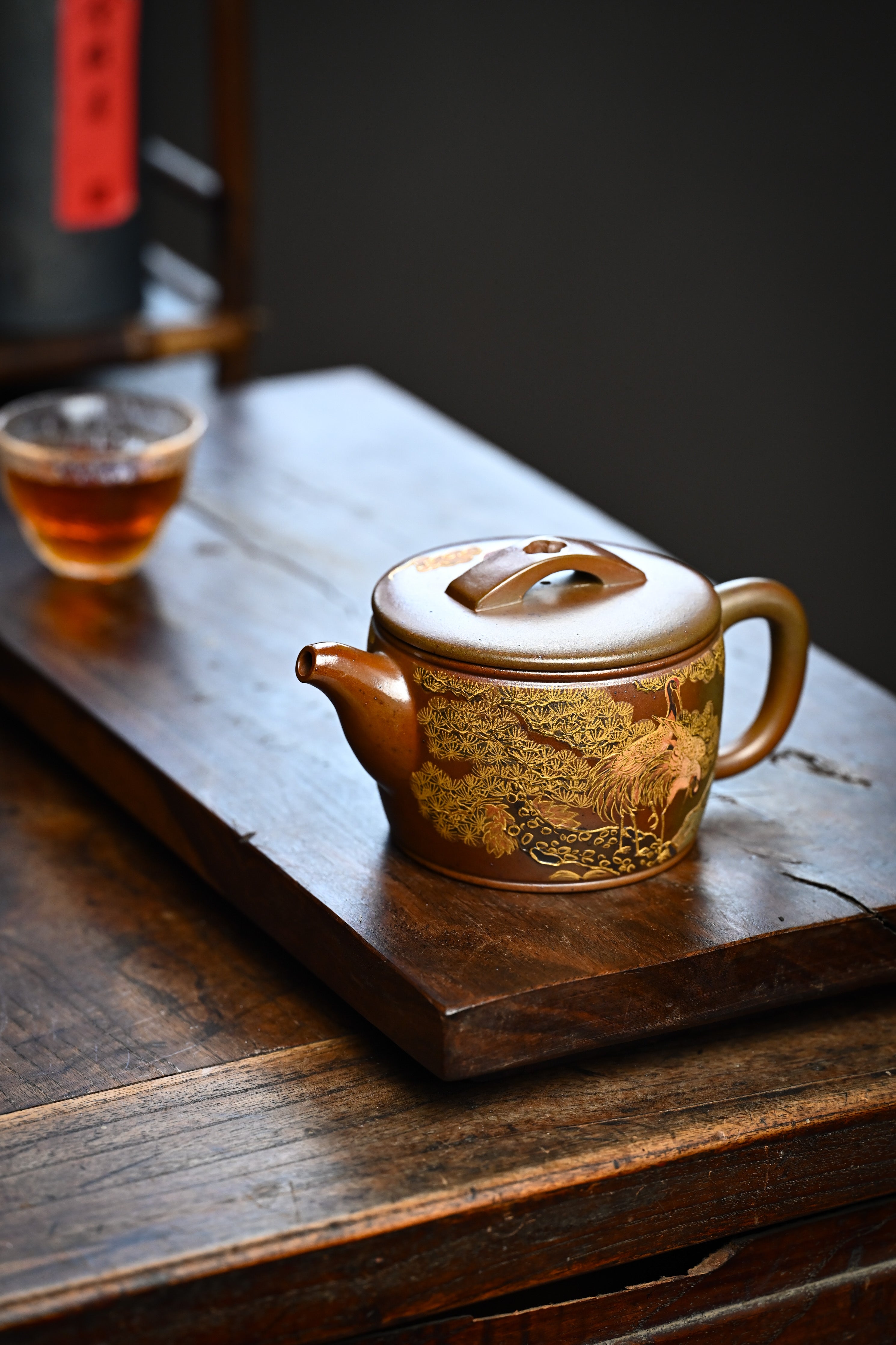 Handmade YANYOO Yixing teapot featuring hand-painted crane and gold enamel, lifestyle left side.