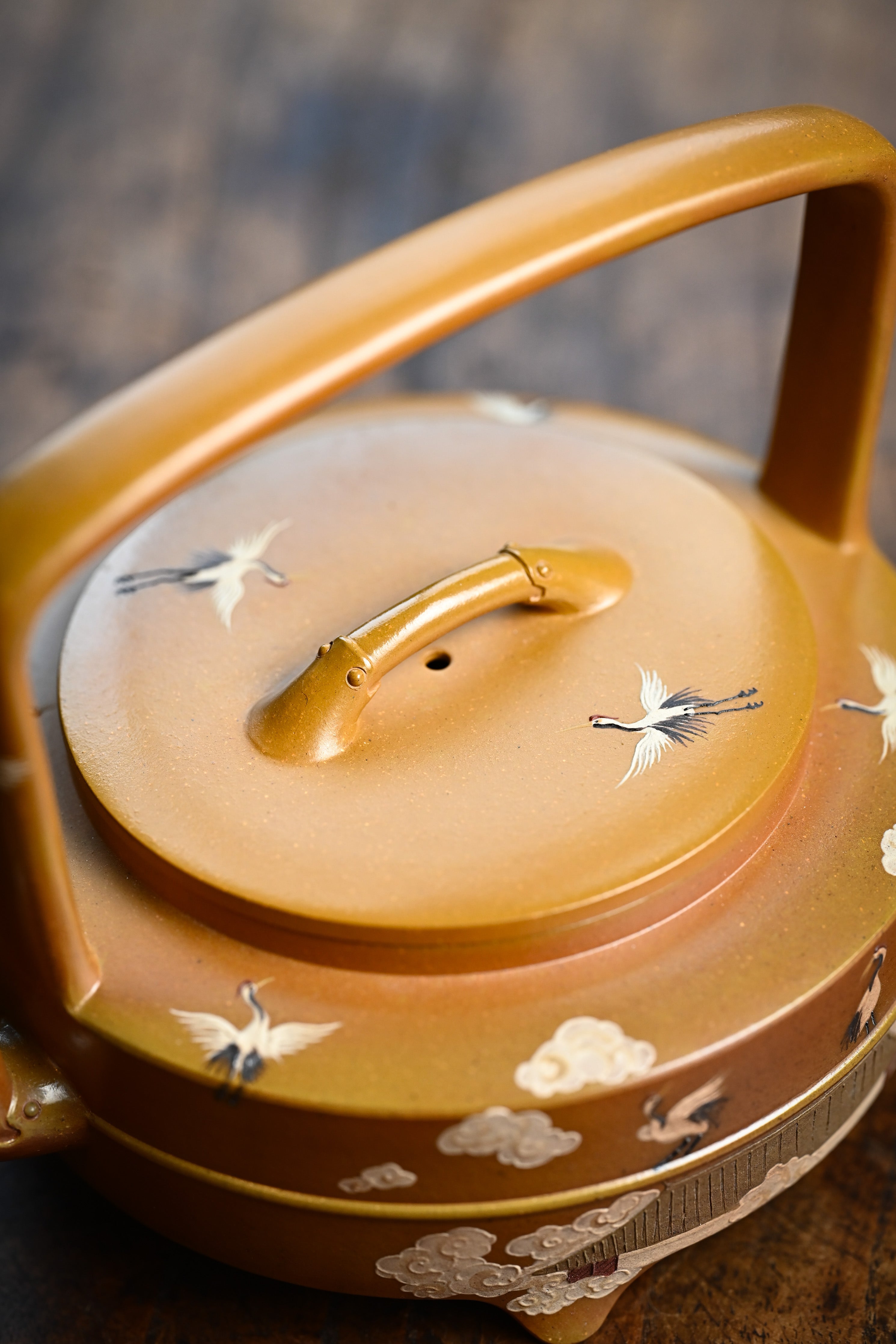 Handmade YANYOO Yixing teapot featuring hand-painted cloud-and-crane motif, lifestyle top side.