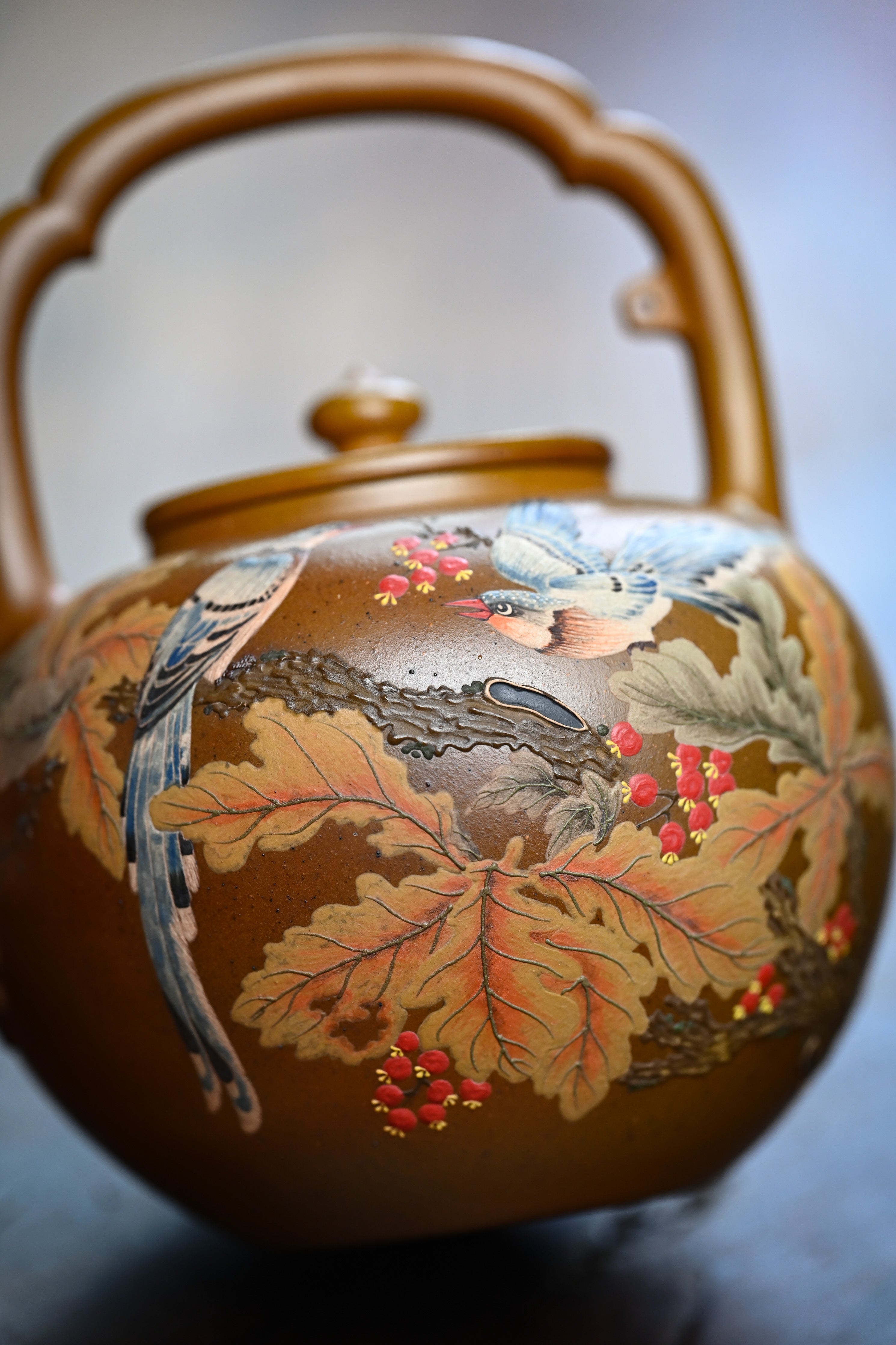 Handmade YANYOO Yixing teapot featuring hand-painted floral and bird motif, lifestyle detail front.