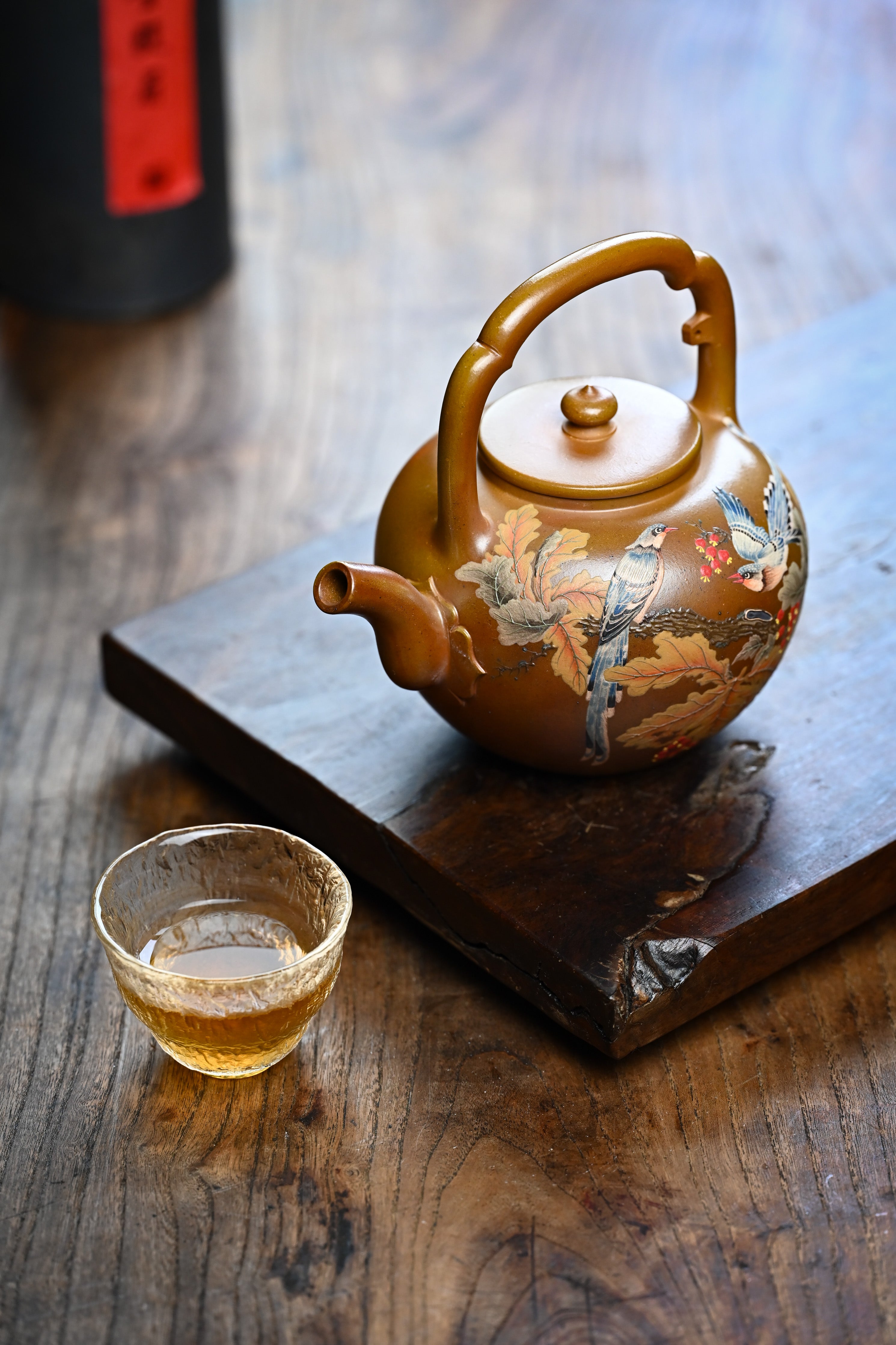 Handmade YANYOO Yixing teapot featuring hand-painted floral and bird motif, lifestyle left side.