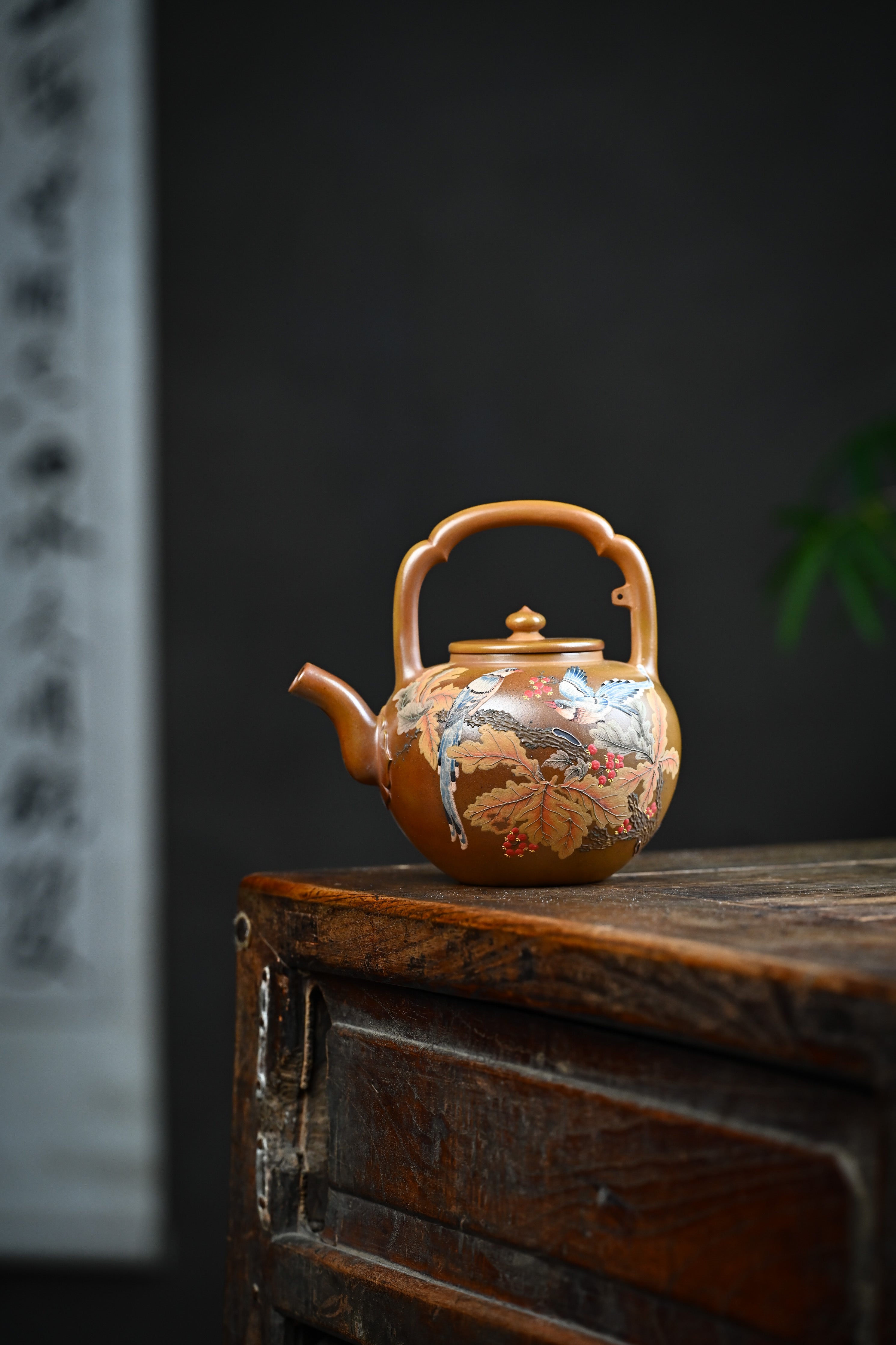 Handmade YANYOO Yixing teapot featuring hand-painted floral and bird motif, lifestyle wide-angle left side.