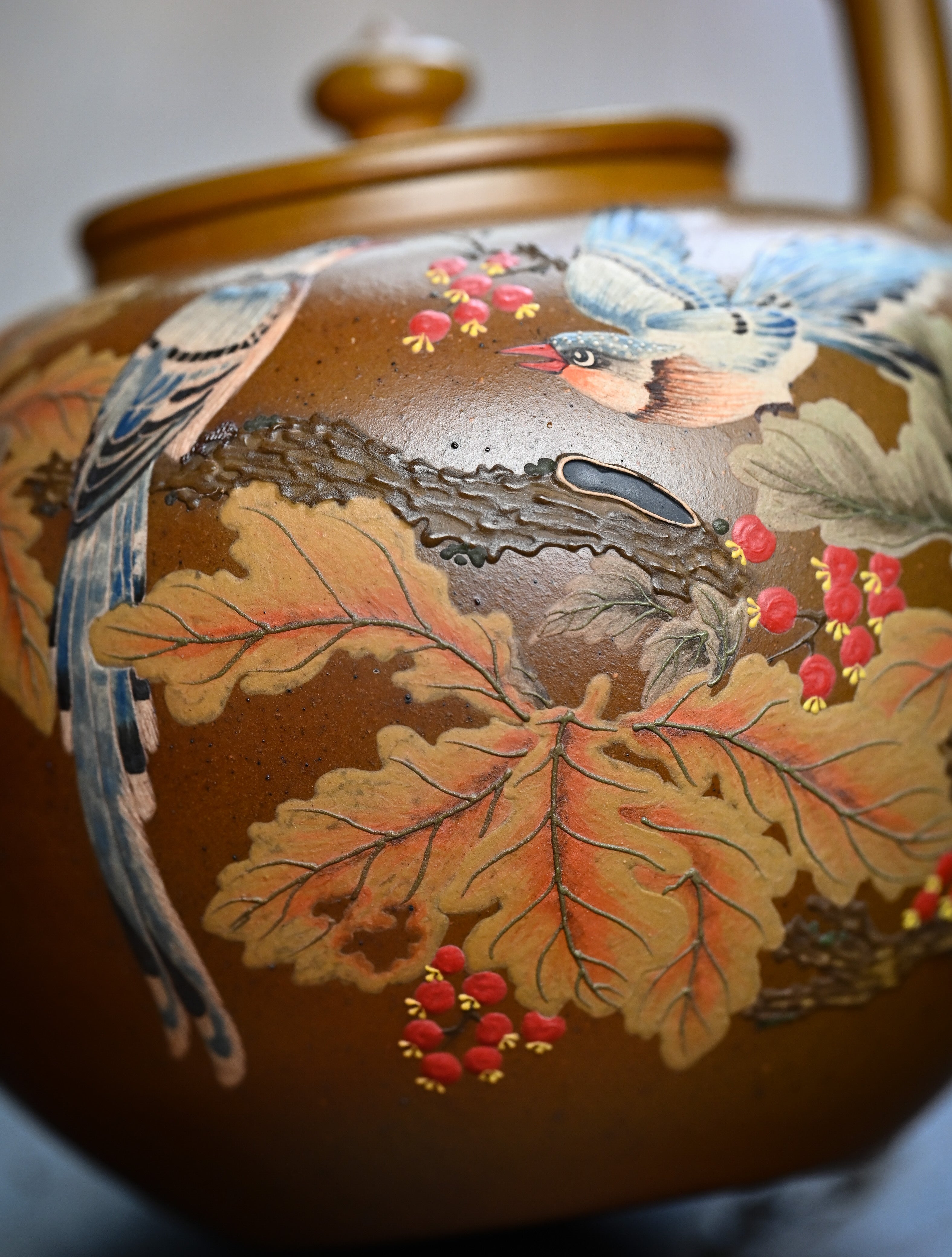 YANYOO handmade wood-fired Yixing teapot featuring hand-painted floral-and-bird motif and lifting handle, lifestyle detail front side.