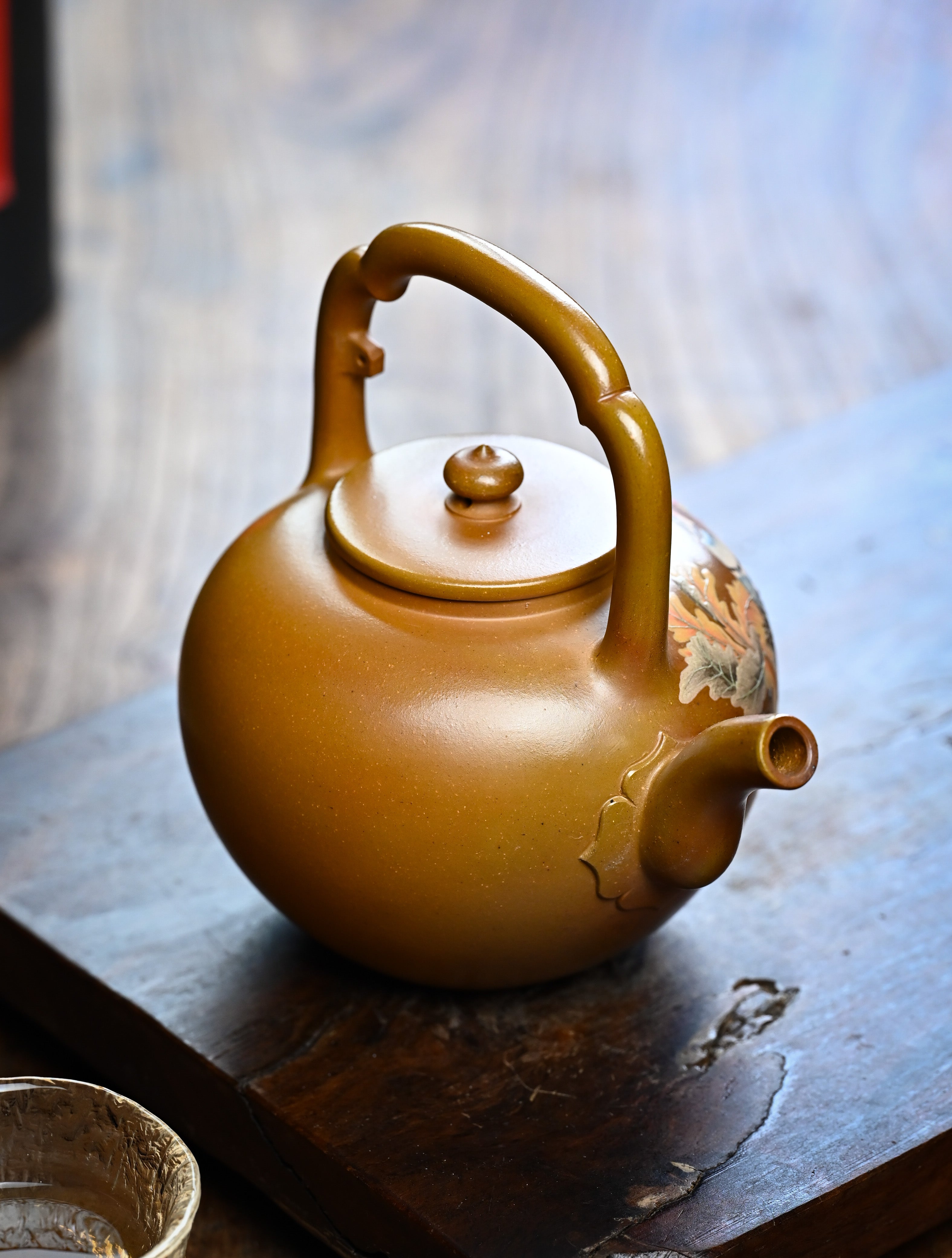 YANYOO handmade wood-fired Yixing teapot featuring hand-painted floral-and-bird motif and lifting handle, lifestyle right side.