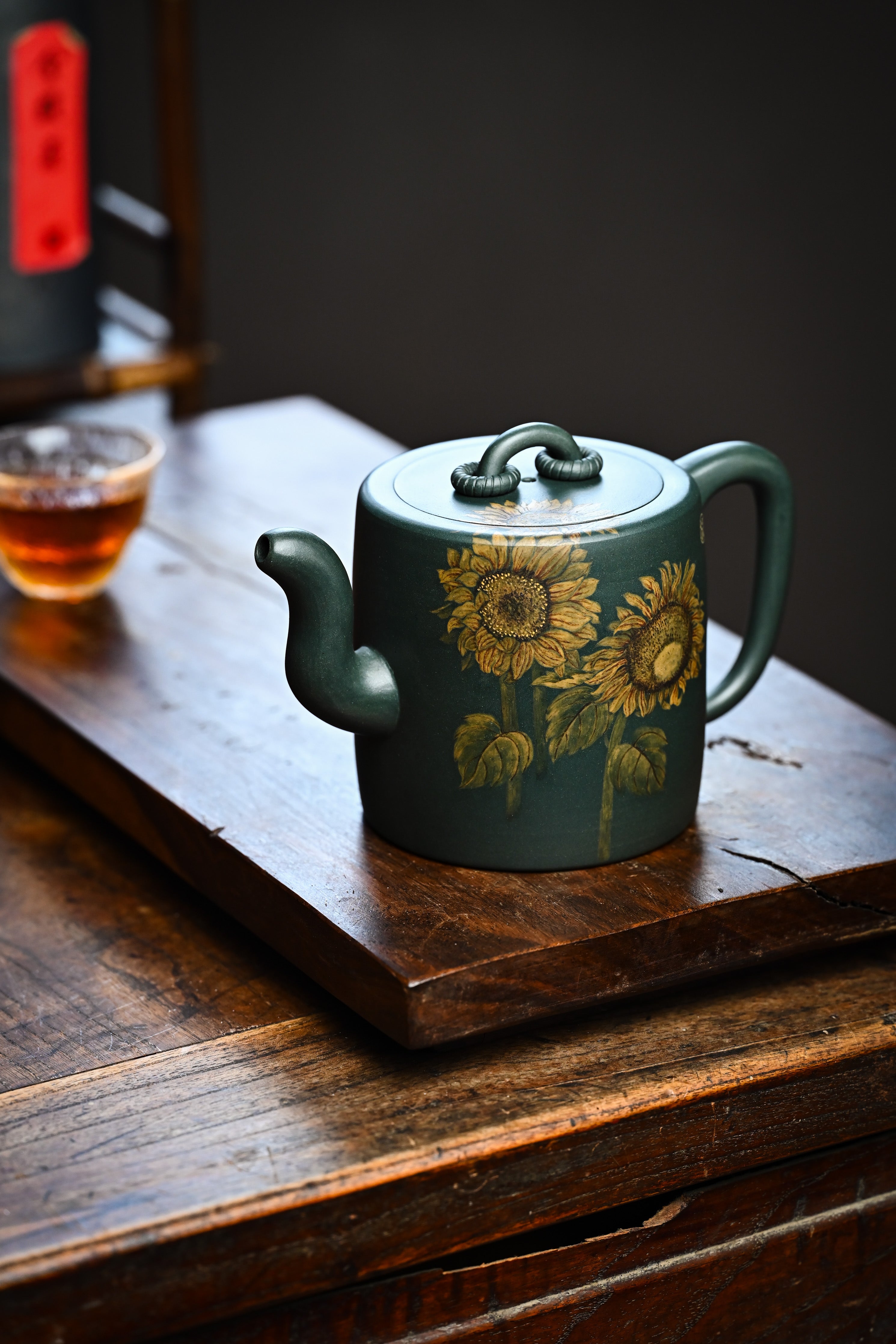 Handmade YANYOO Yixing teapot featuring aged green clay and sunflower design, lifestyle left side.