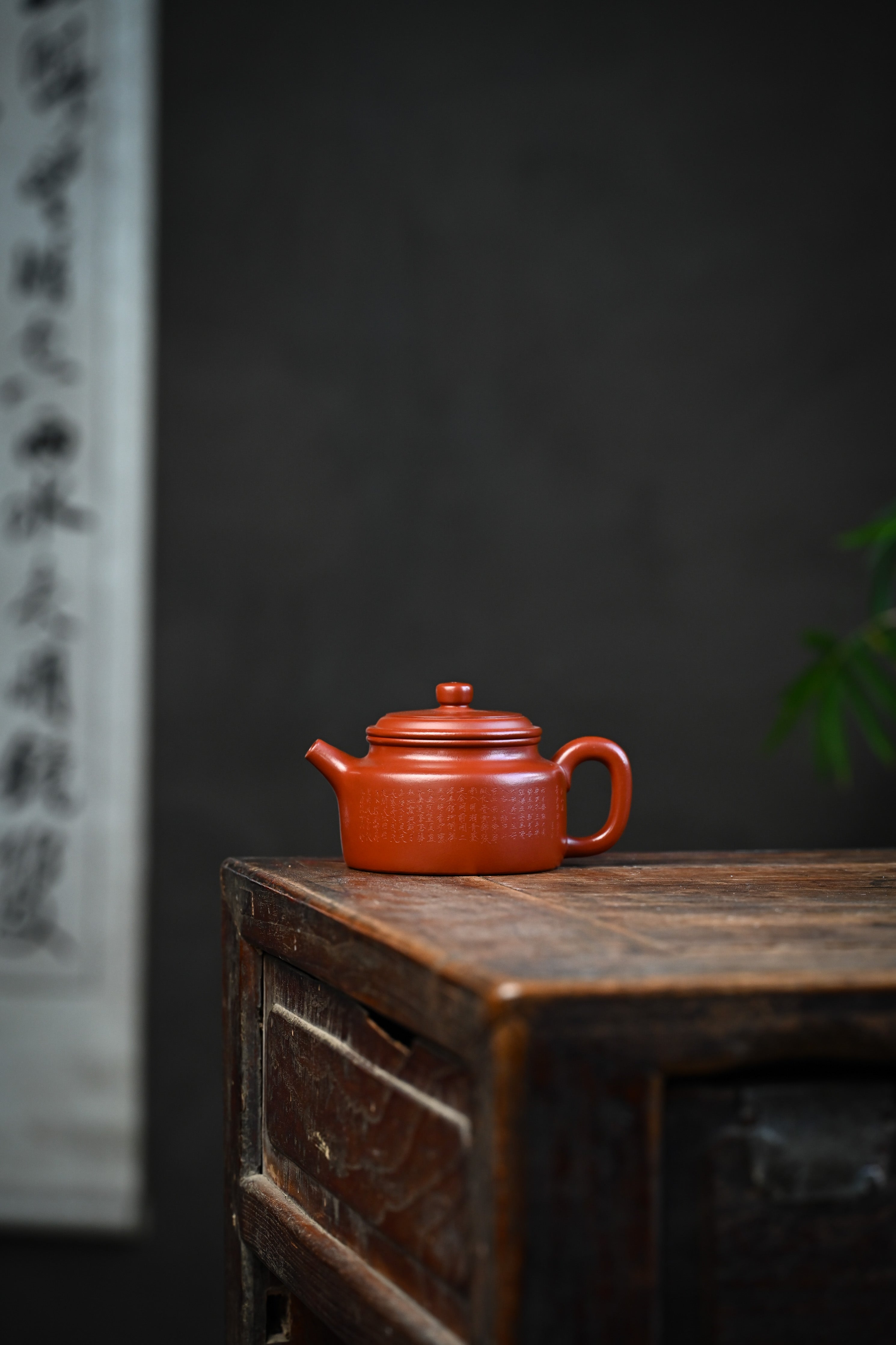 Handmade YANYOO Yixing teapot featuring Zhuni clay and Chinese landscape engraving, lifestyle wide-angle left side.