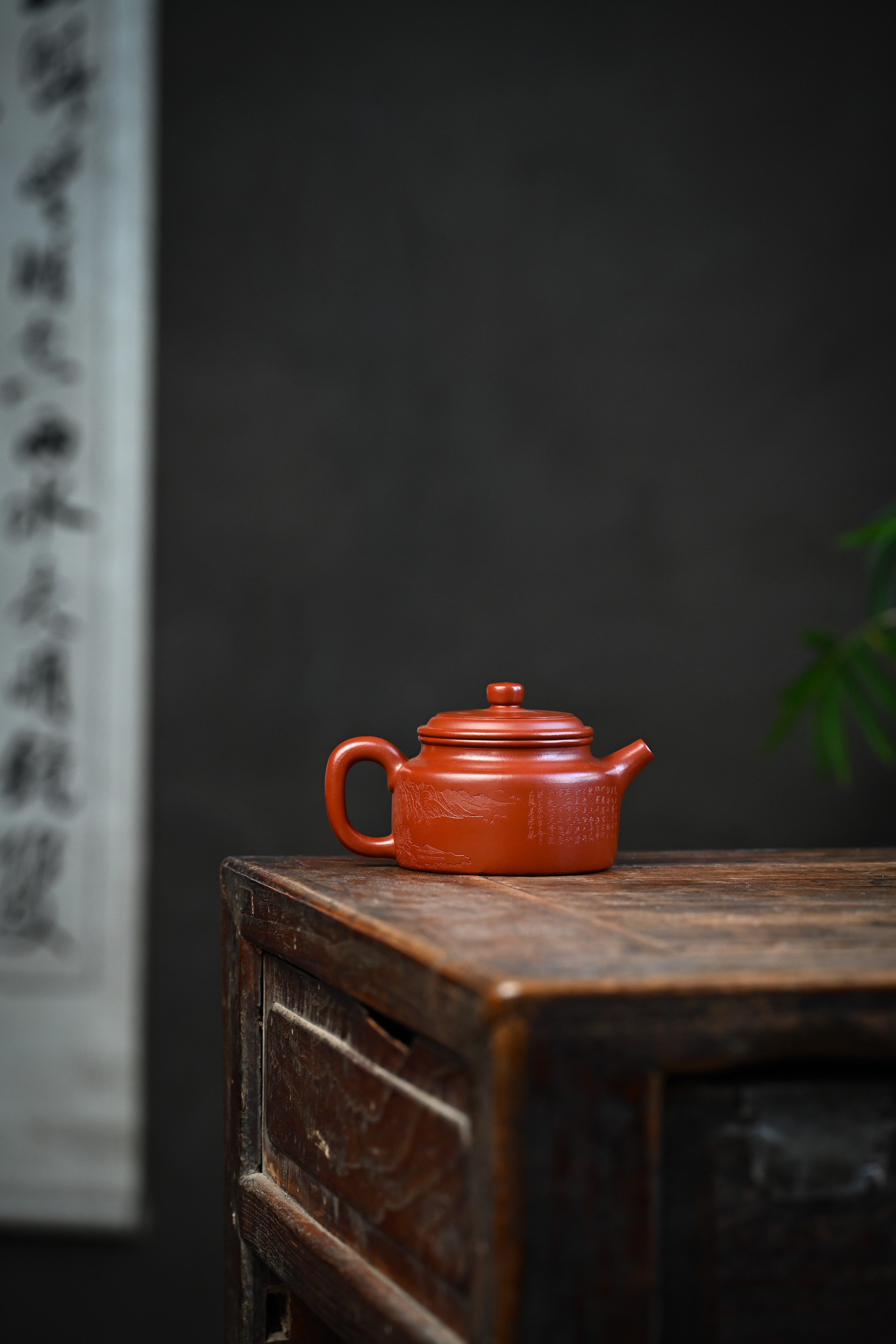 Handmade YANYOO Yixing teapot featuring Zhuni clay and Chinese landscape engraving, lifestyle wide-angle right side.