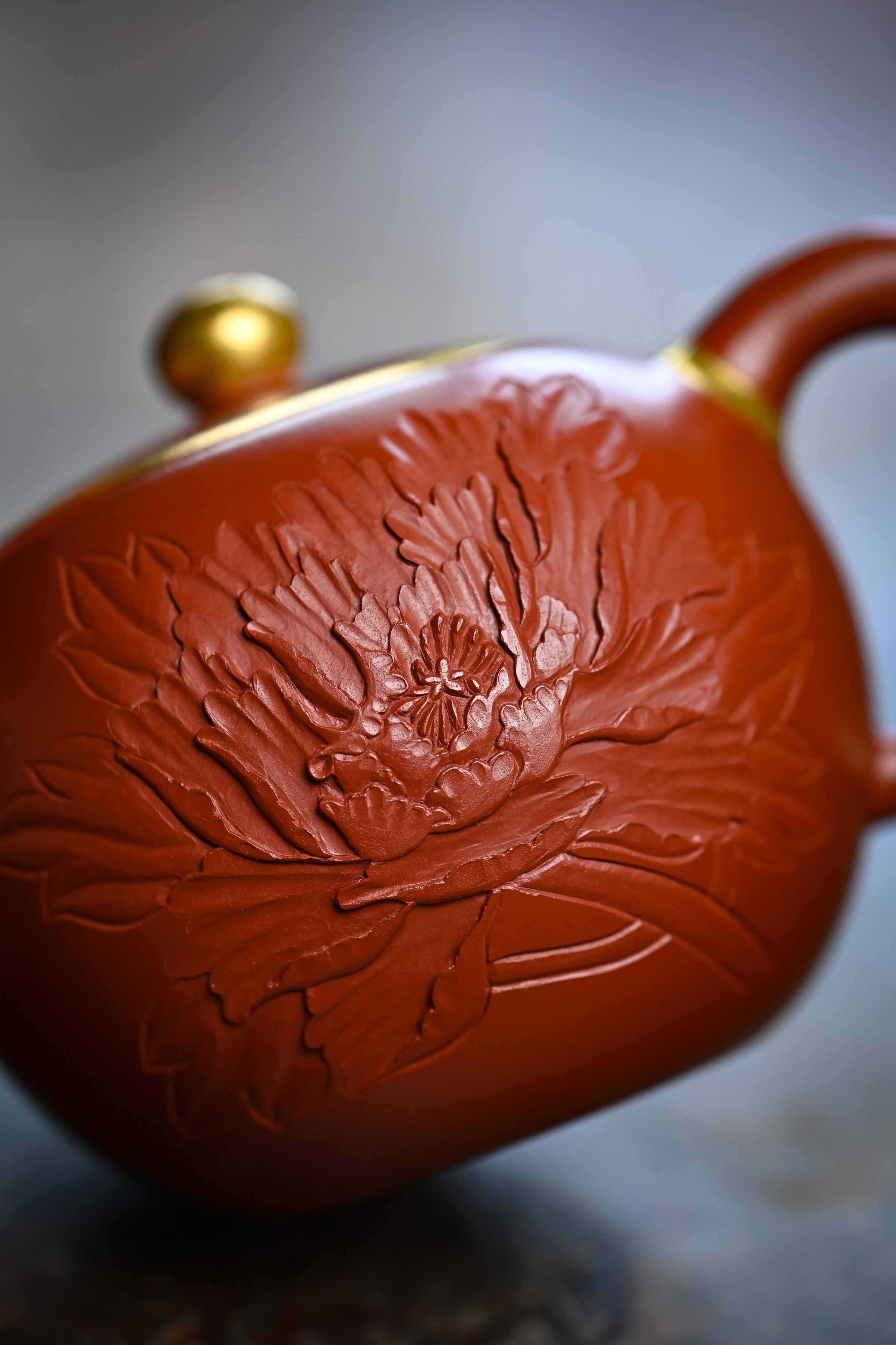 Handmade YANYOO Yixing teapot featuring Zhuni clay and relief engraving, lifestyle detail front.