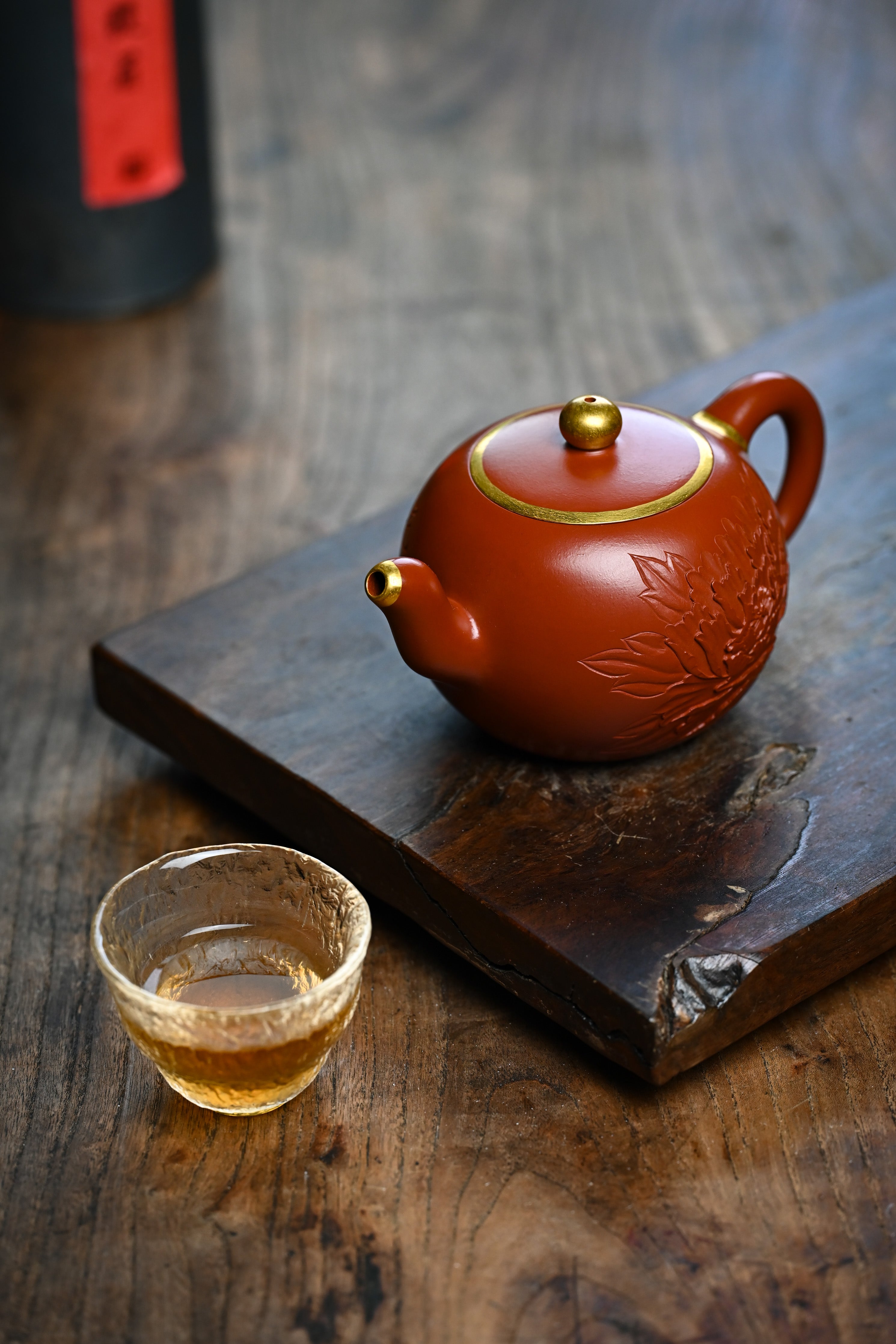 Handmade YANYOO Yixing teapot featuring Zhuni clay and relief engraving, lifestyle left side.