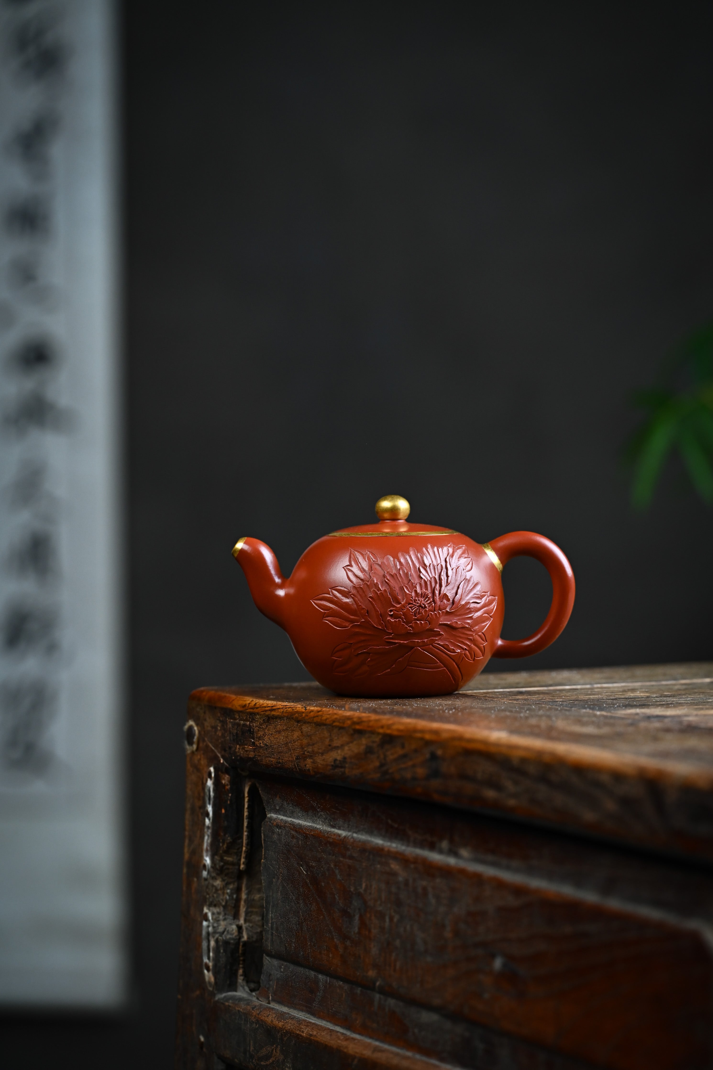 Handmade YANYOO Yixing teapot featuring Zhuni clay and relief engraving, lifestyle wide-angle left side.