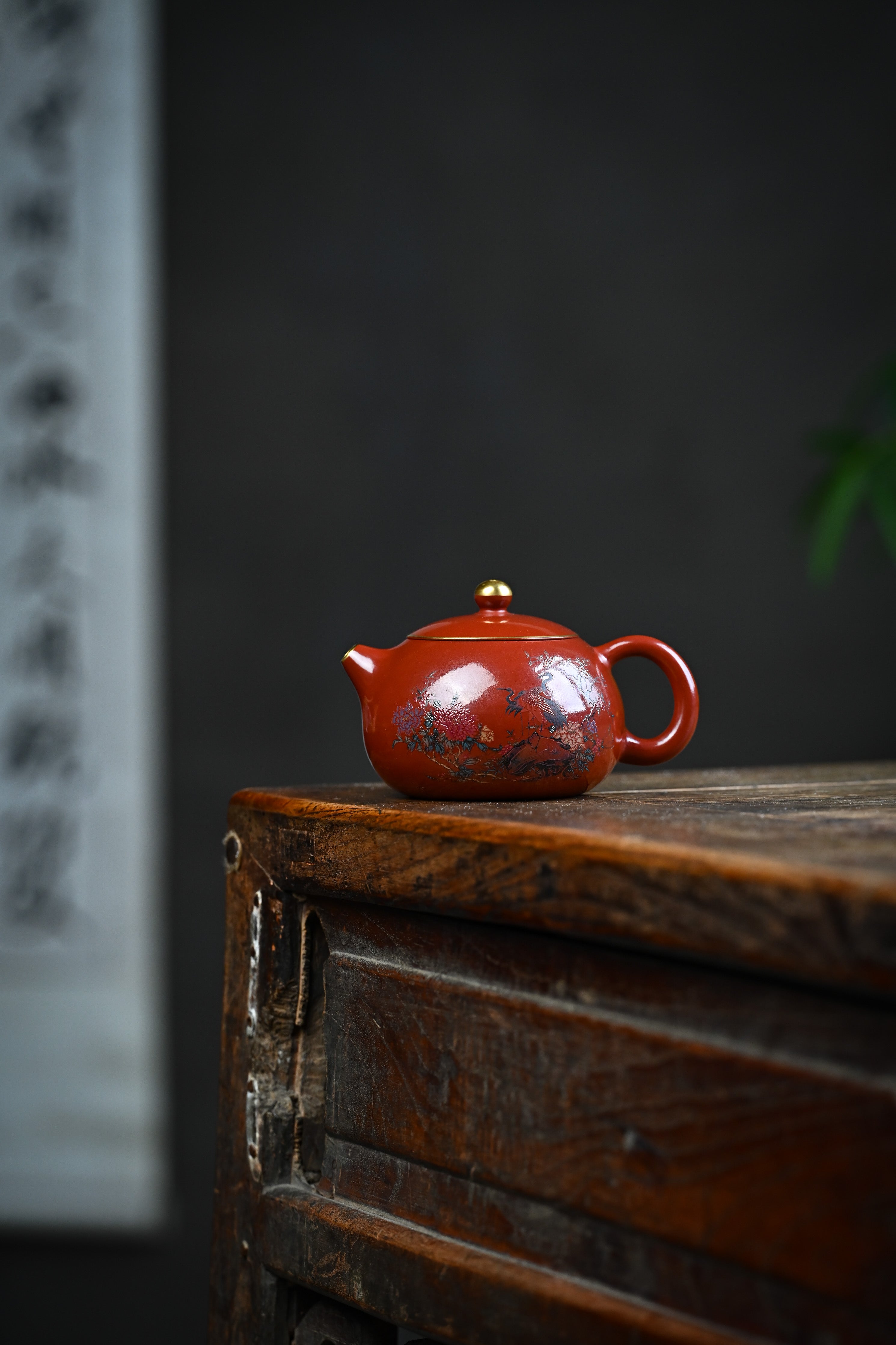 Handmade YANYOO Yixing teapot featuring Zhuni clay, hand-painted pattern and water-polished craftsmanship, lifestyle wide-angle left side.