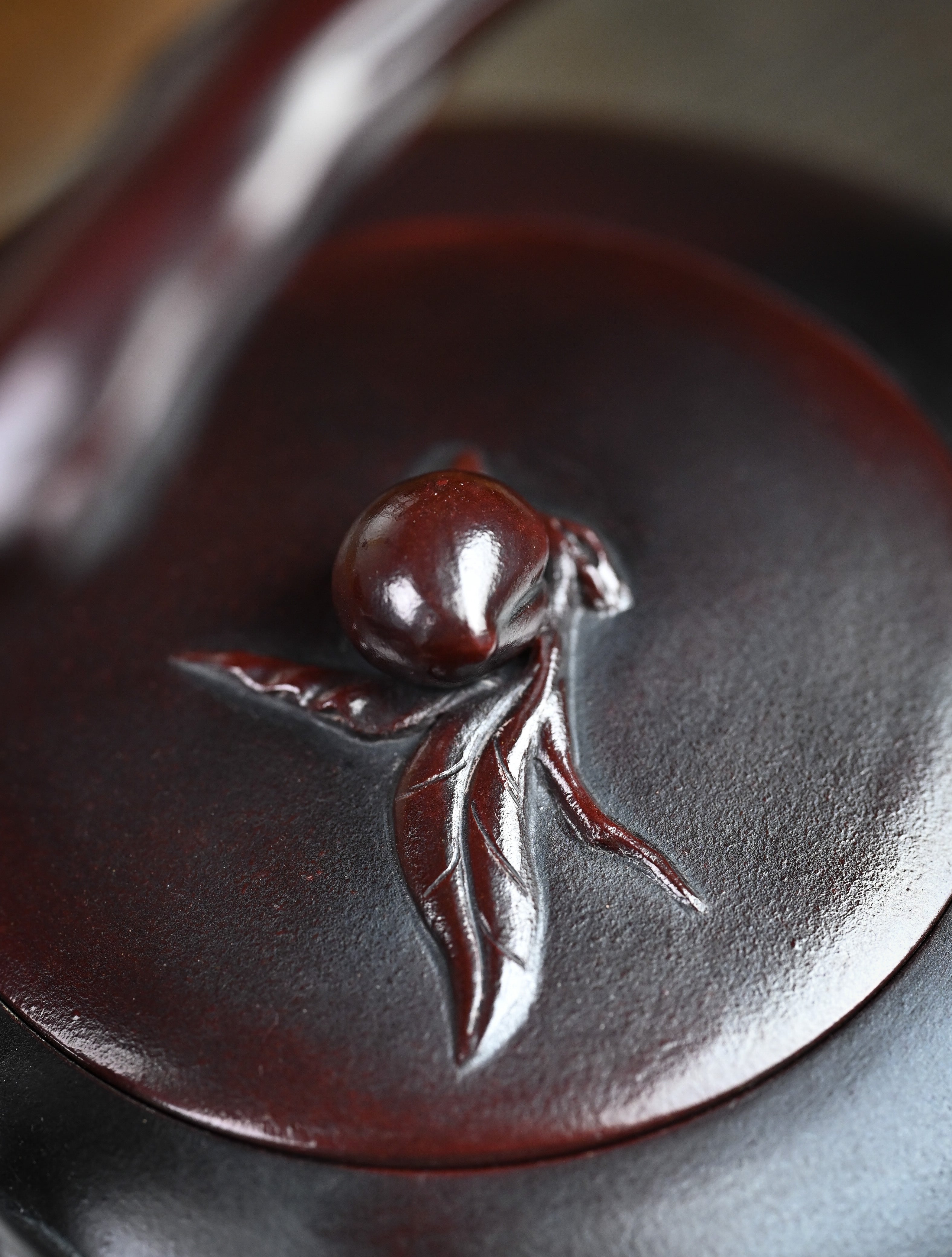 YANYOO handmade Yixing teapot featuring aged Wuni clay, lifting handle and peach sculpture, lifestyle detail.