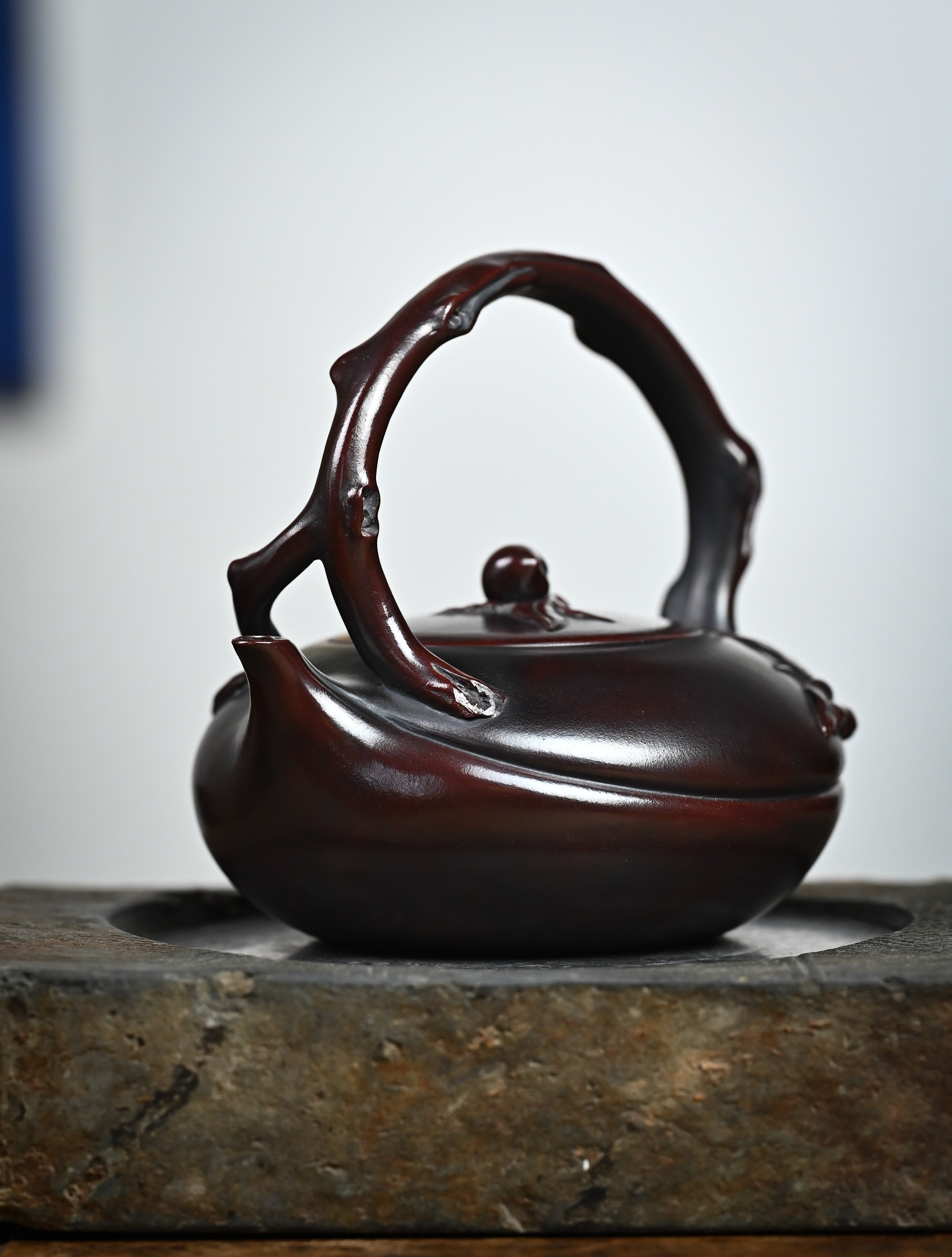 YANYOO handmade Yixing teapot featuring aged Wuni clay, lifting handle and peach sculpture, lifestyle front side.